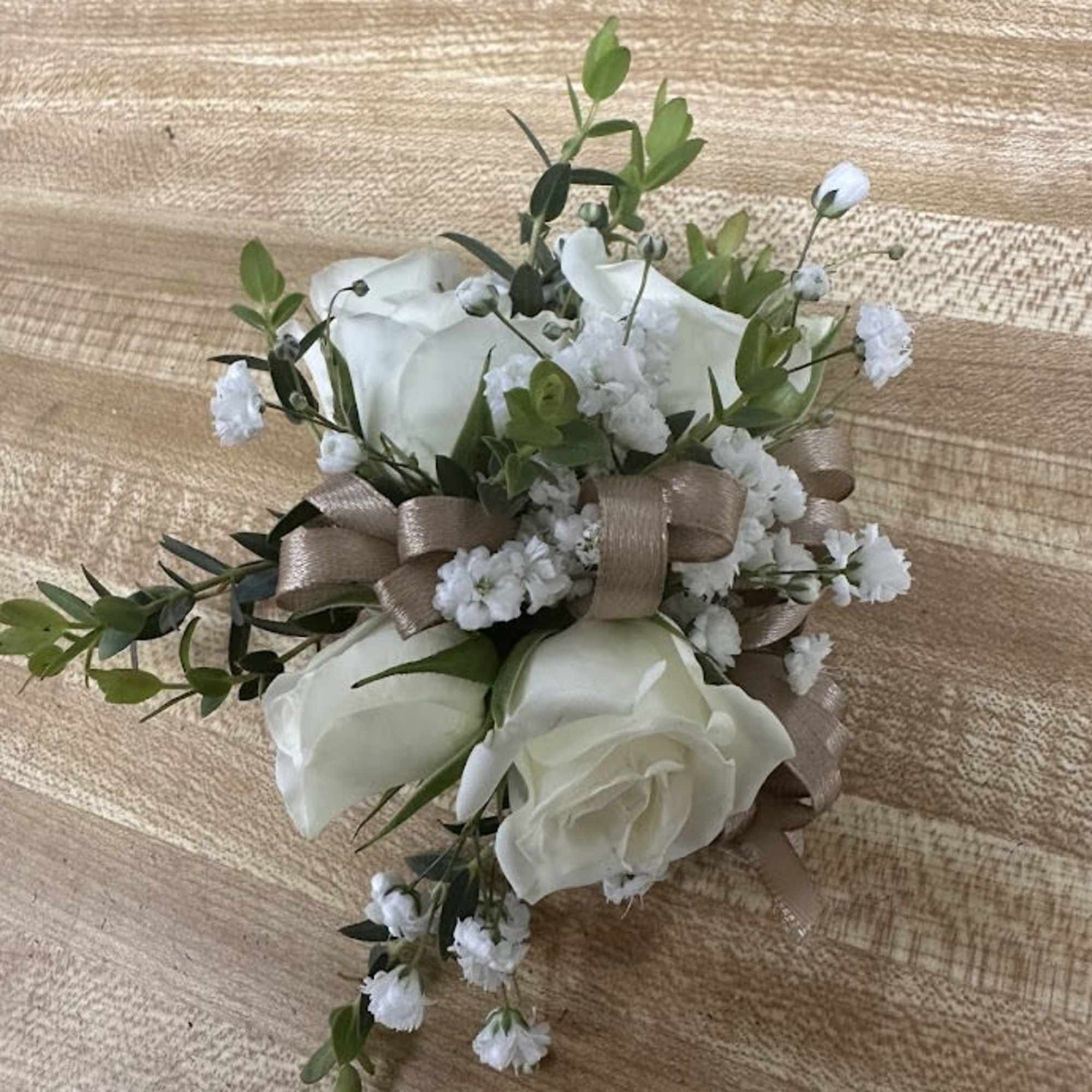 A delicate white rose corsage and matching boutonniere set that reads as