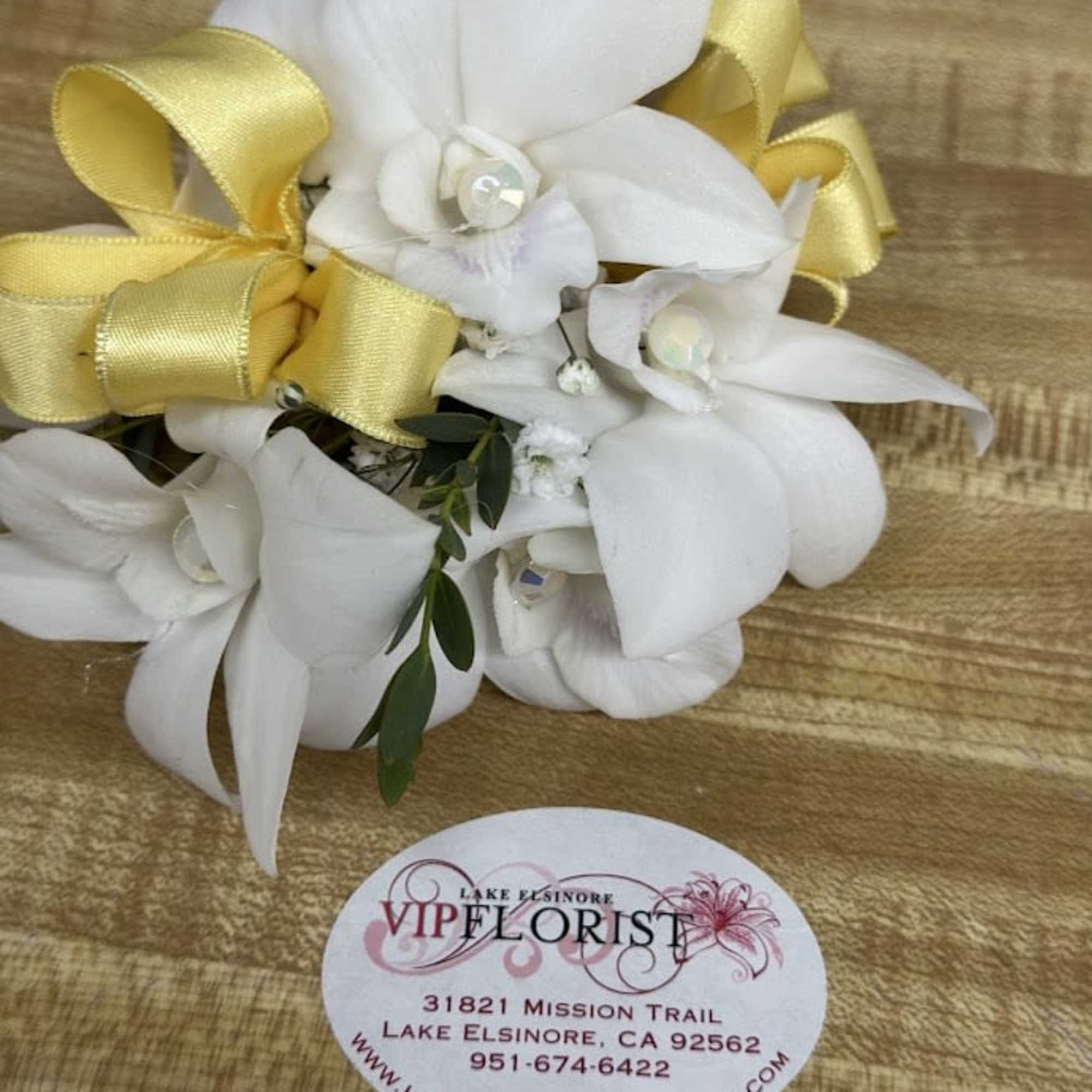 A delicate white rose corsage and matching boutonniere set that reads as