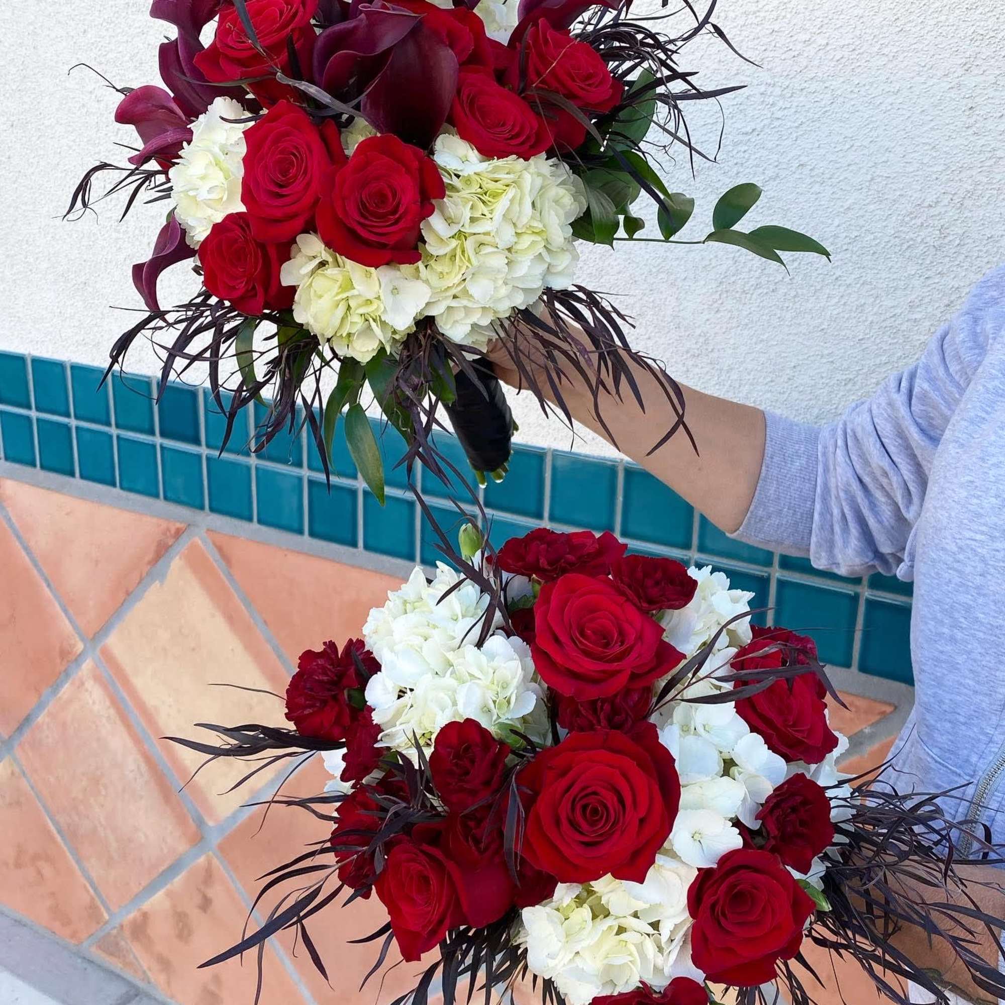 Two red rose bouquets with white hydrangeas and dark foliage