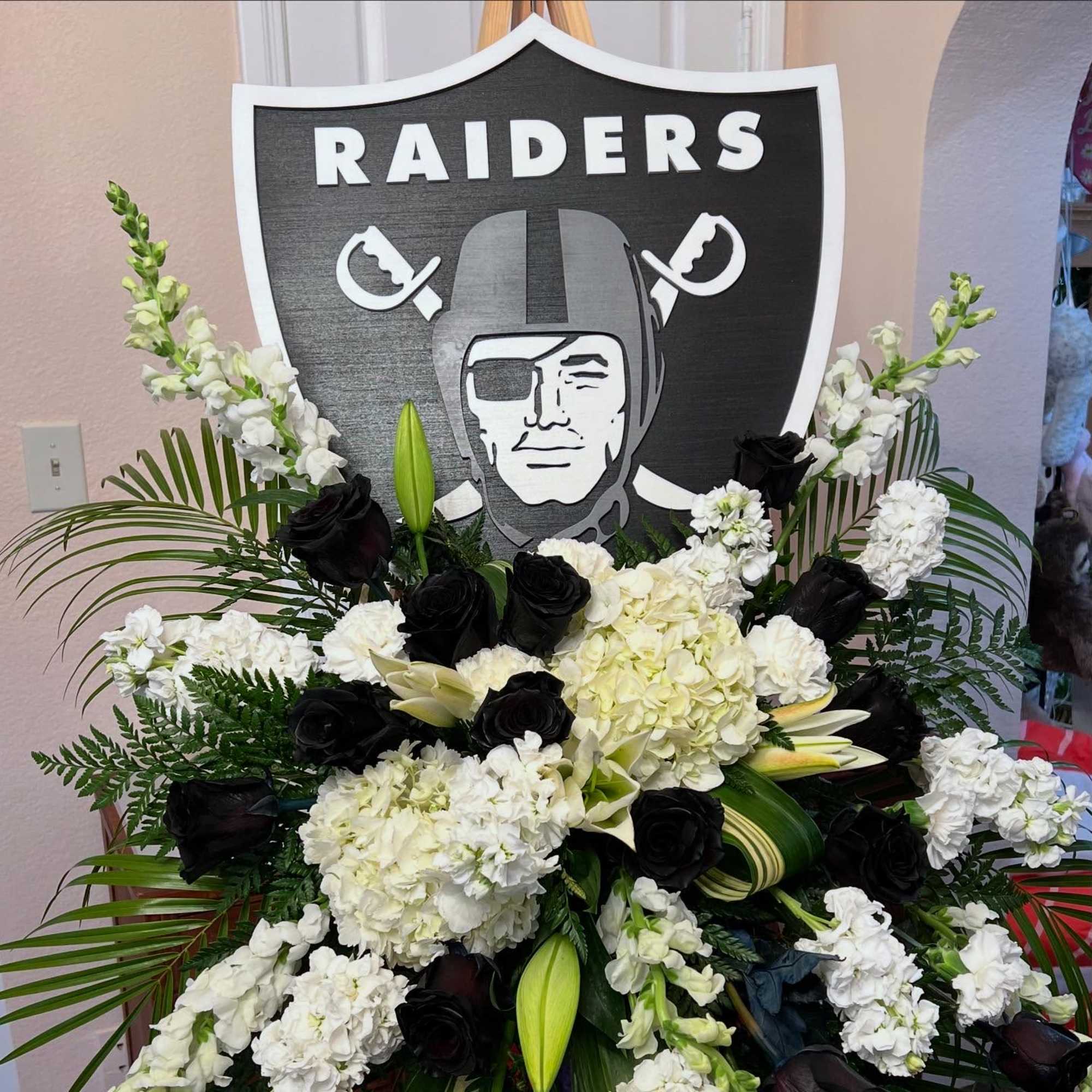 Black and white floral arrangement with Raiders sign backdrop