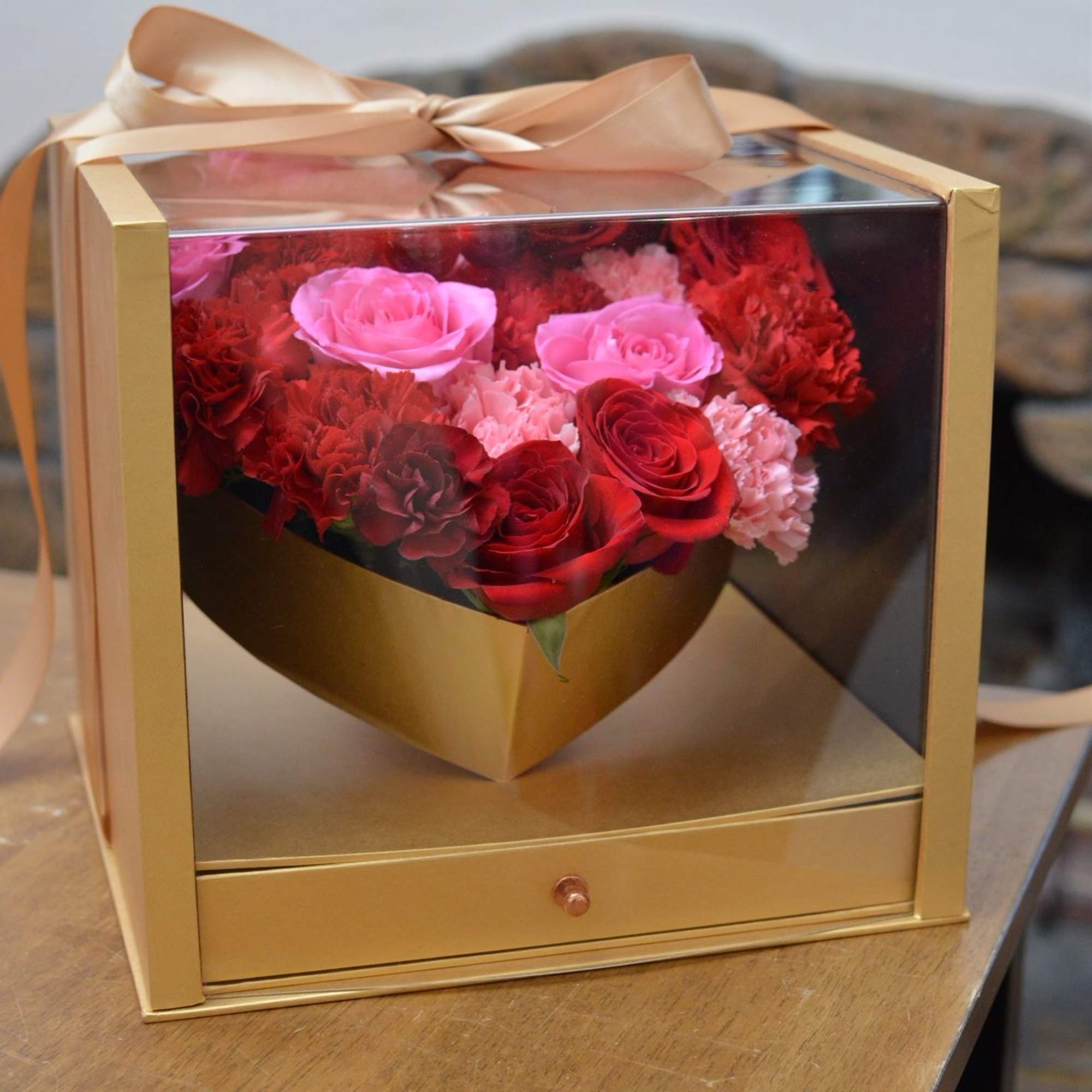 Pink and red roses in a gold gift box with a ribbon