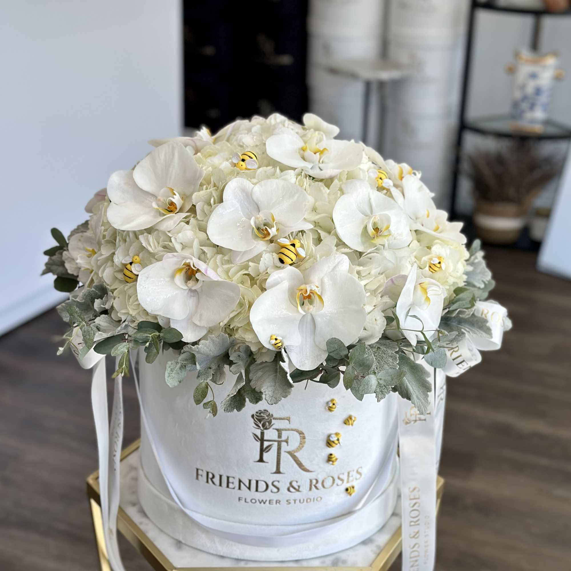 White orchid and hydrangea arrangement in a round hatbox with ribbon