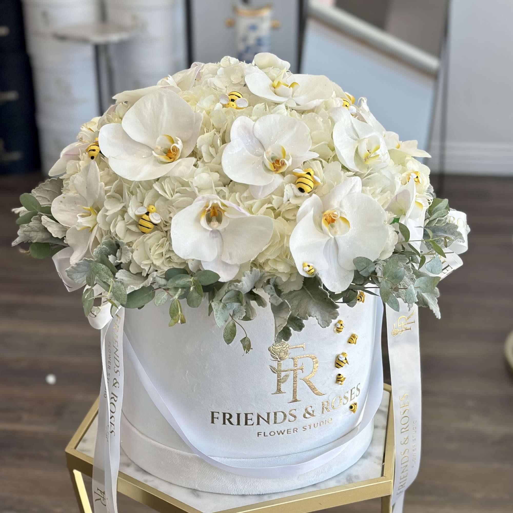 White orchid and hydrangea arrangement in a round hatbox