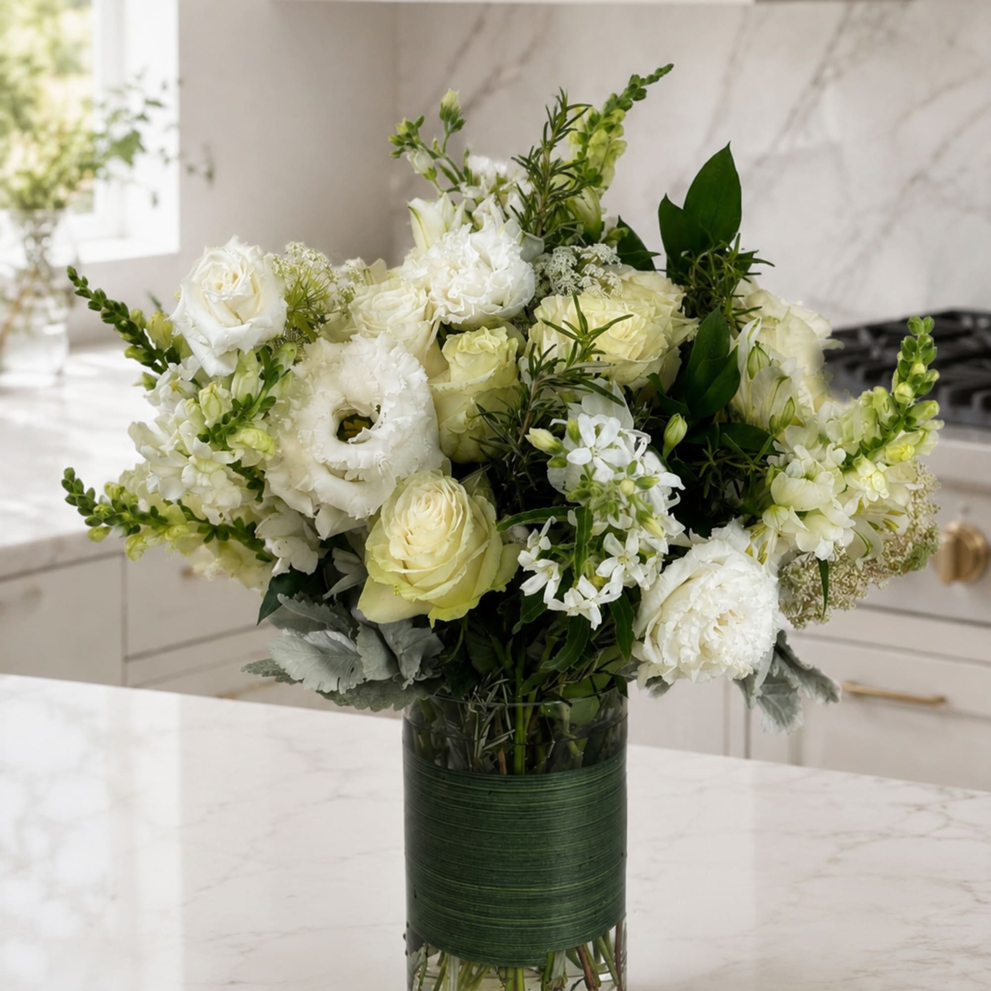 White floral arrangement in a glass vase with green accents