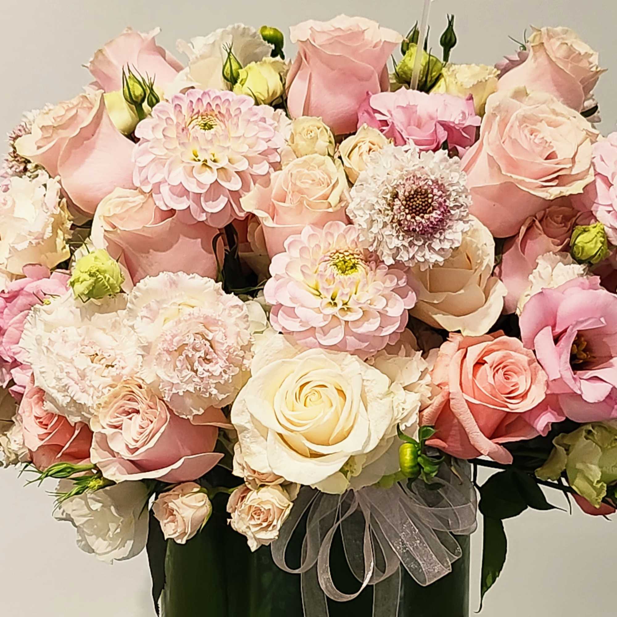 Bouquet of pink and cream roses with dahlias in a vase