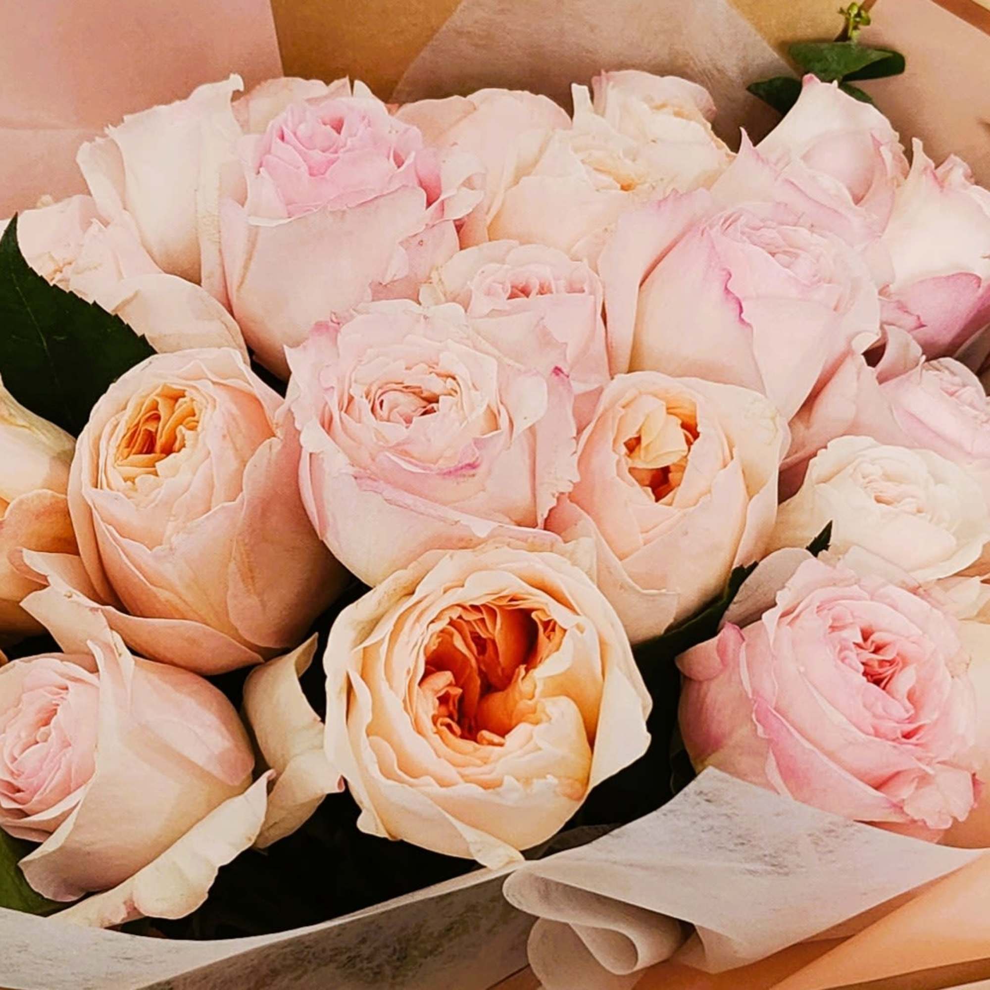Bouquet of pale pink and peach roses wrapped in paper