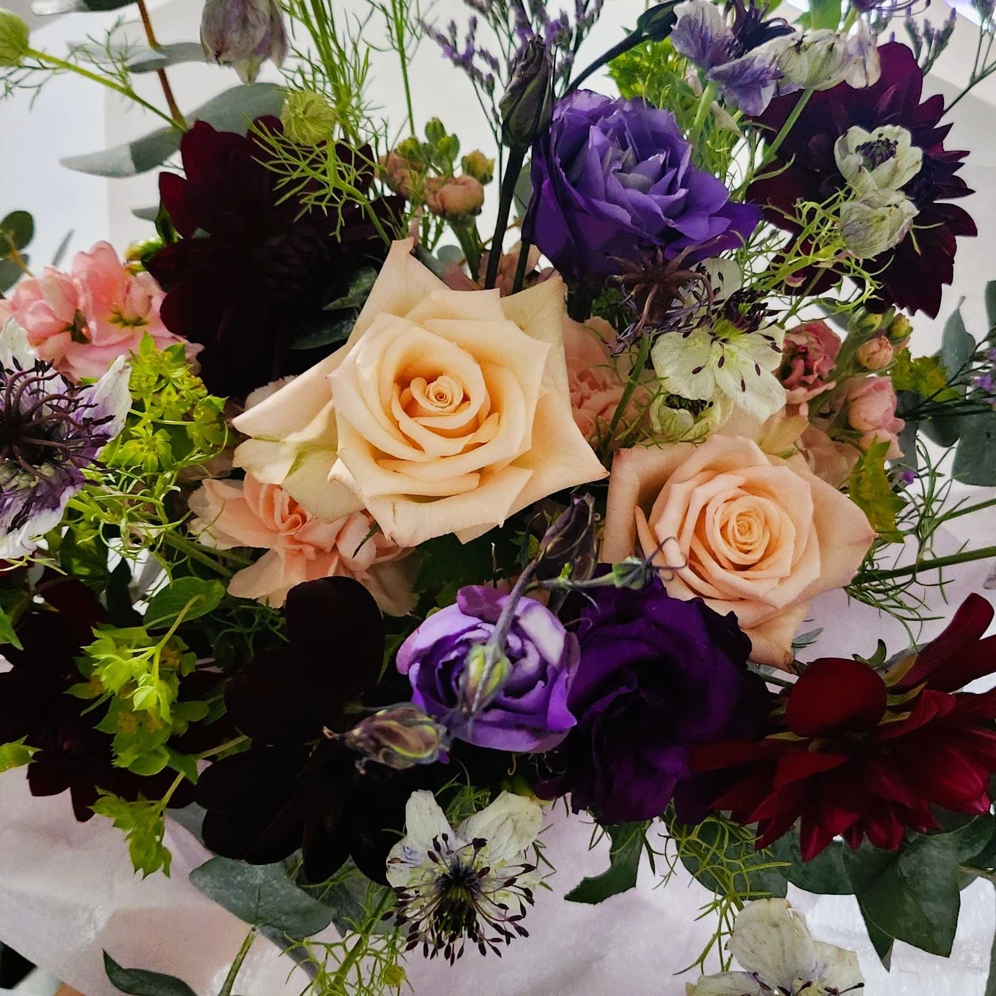 Bouquet of peach and purple roses with mixed accent flowers