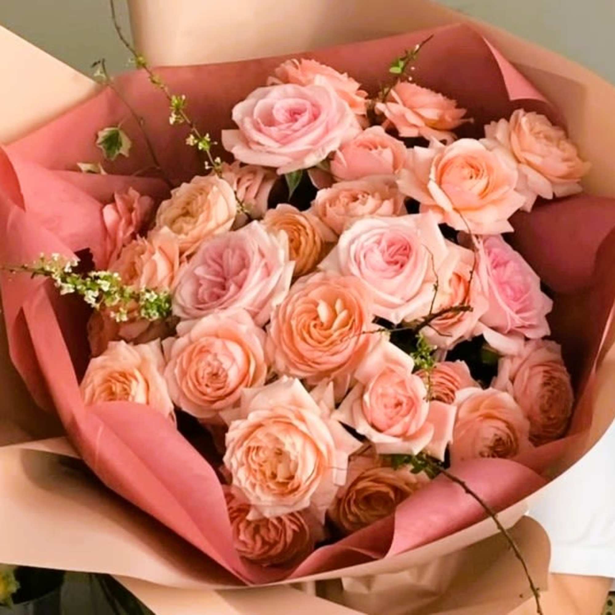 Bouquet of blush and peach roses wrapped in pink paper