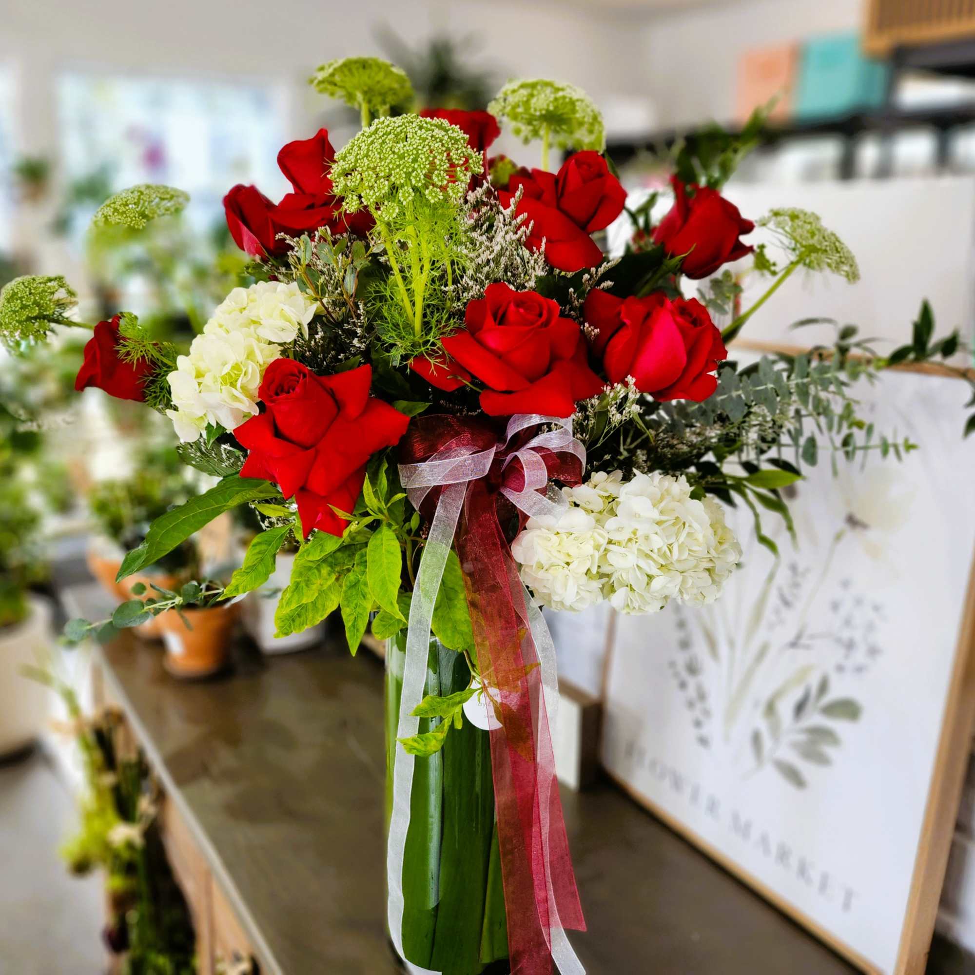 Bouquet of red roses and white hydrangeas with ribbon in a glass vase