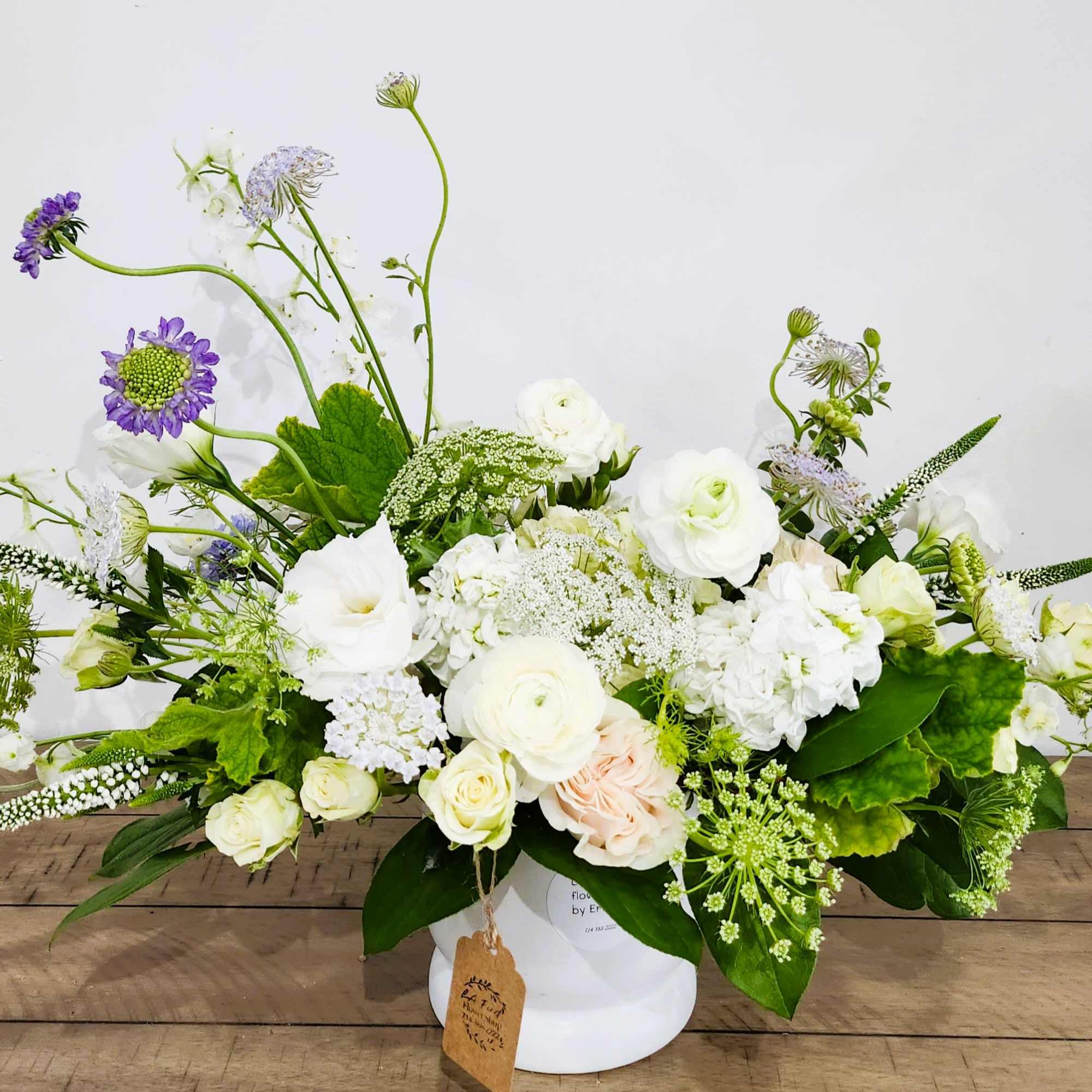 White and purple mixed flower arrangement in a white vase