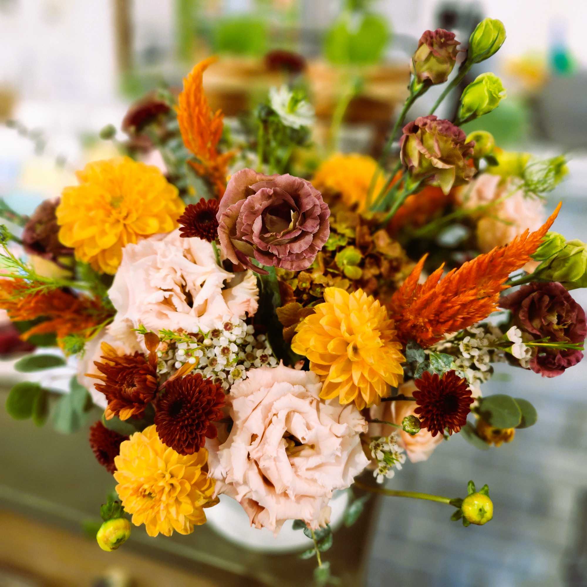 Bouquet of yellow, blush, and burgundy flowers in a vase