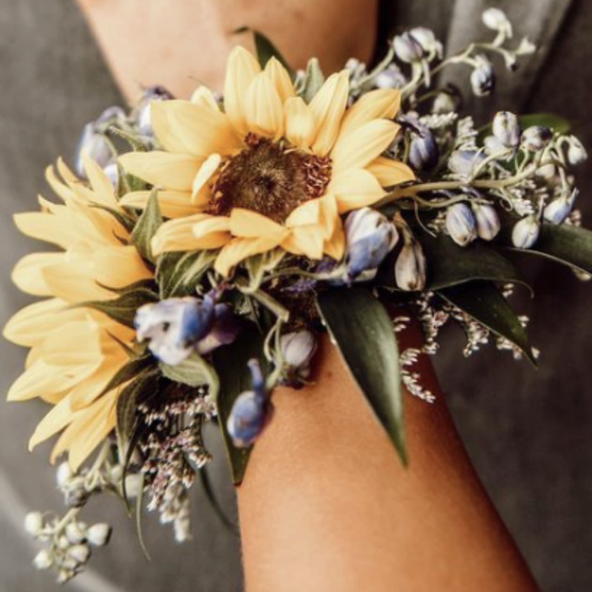 Yellow sunflower wrist corsage with blue buds and greenery