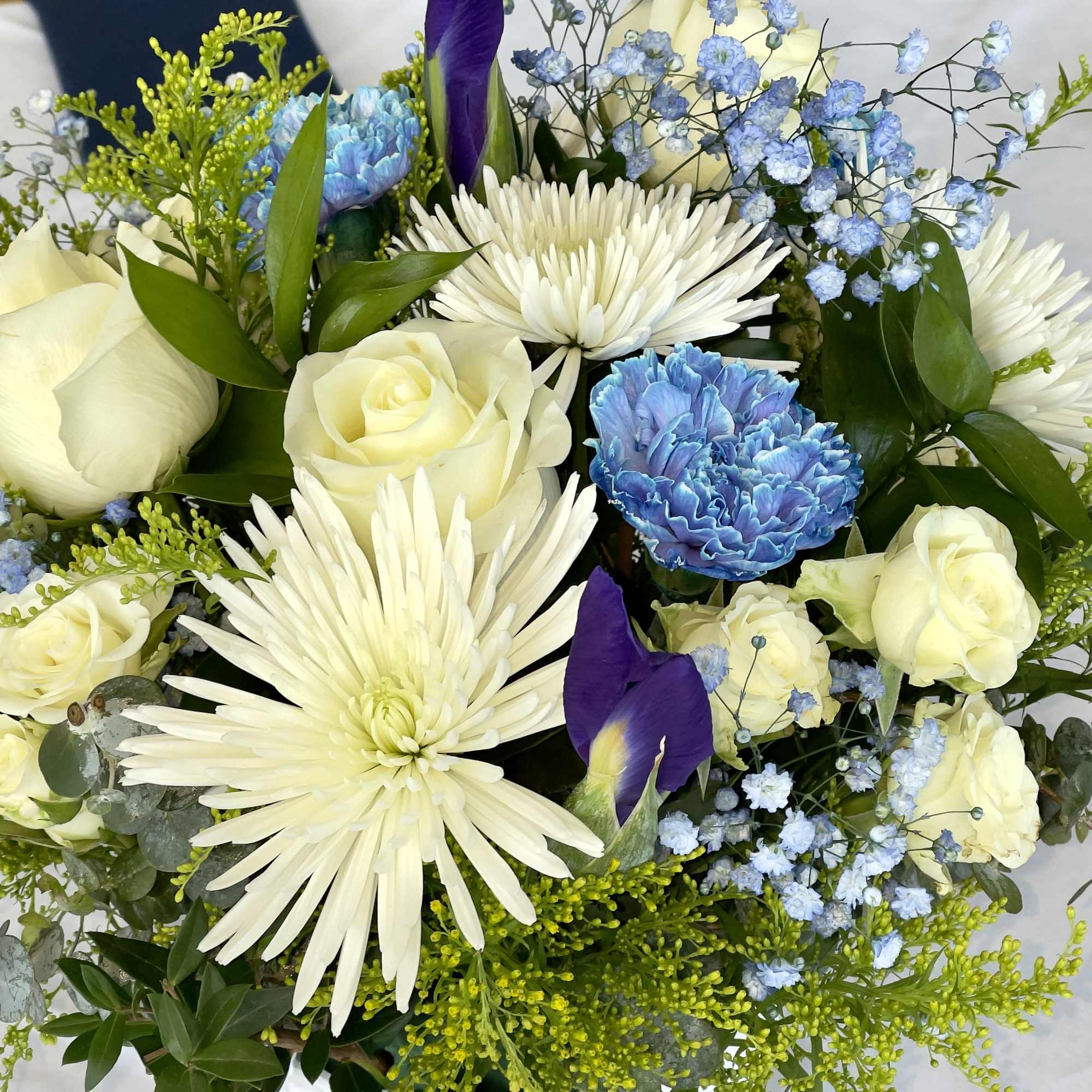 Arrangement of white roses and spider mums with blue carnations and purple irises