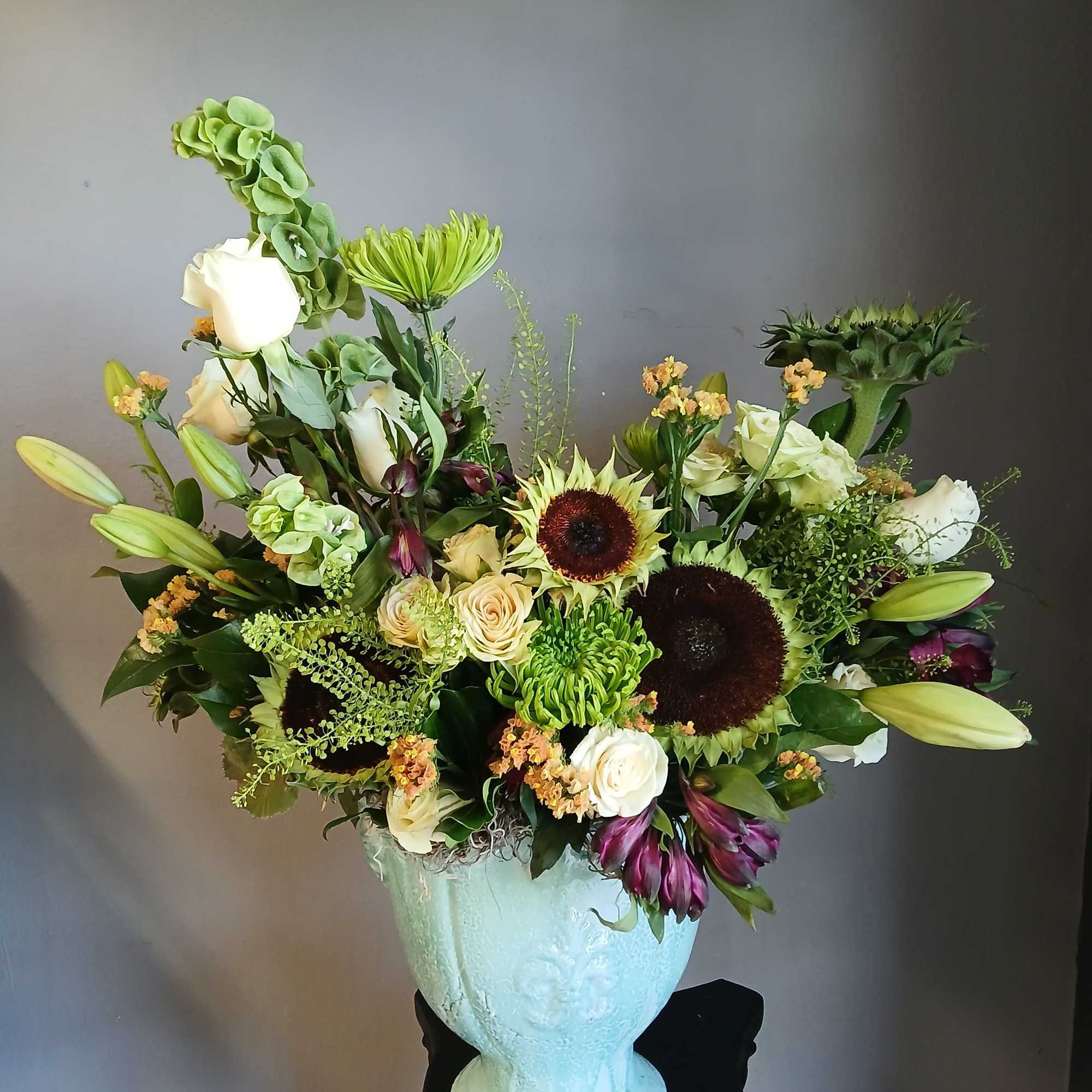 Large mixed flower arrangement in a pale blue vase