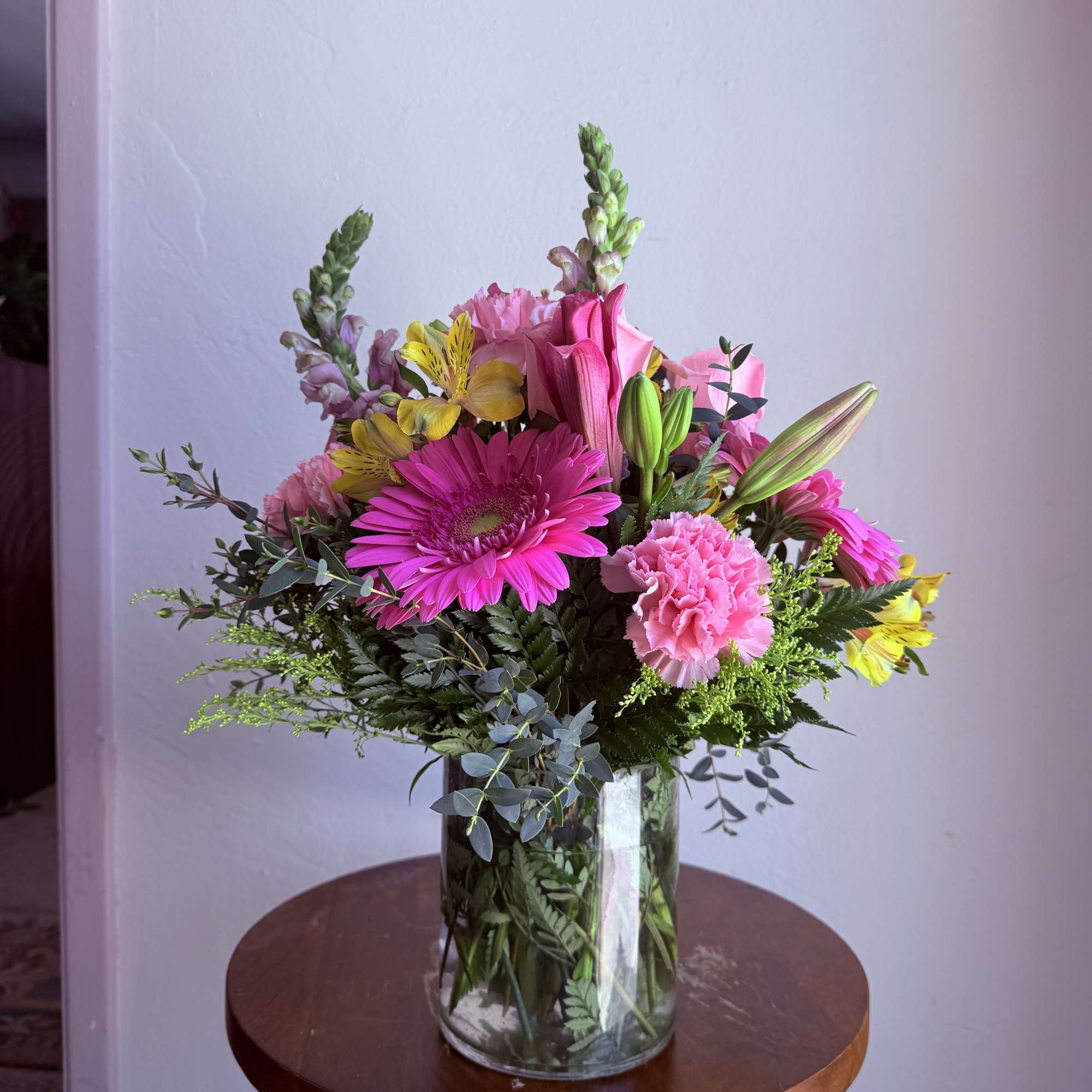 Mixed bouquet of pink and yellow flowers in a clear glass vase