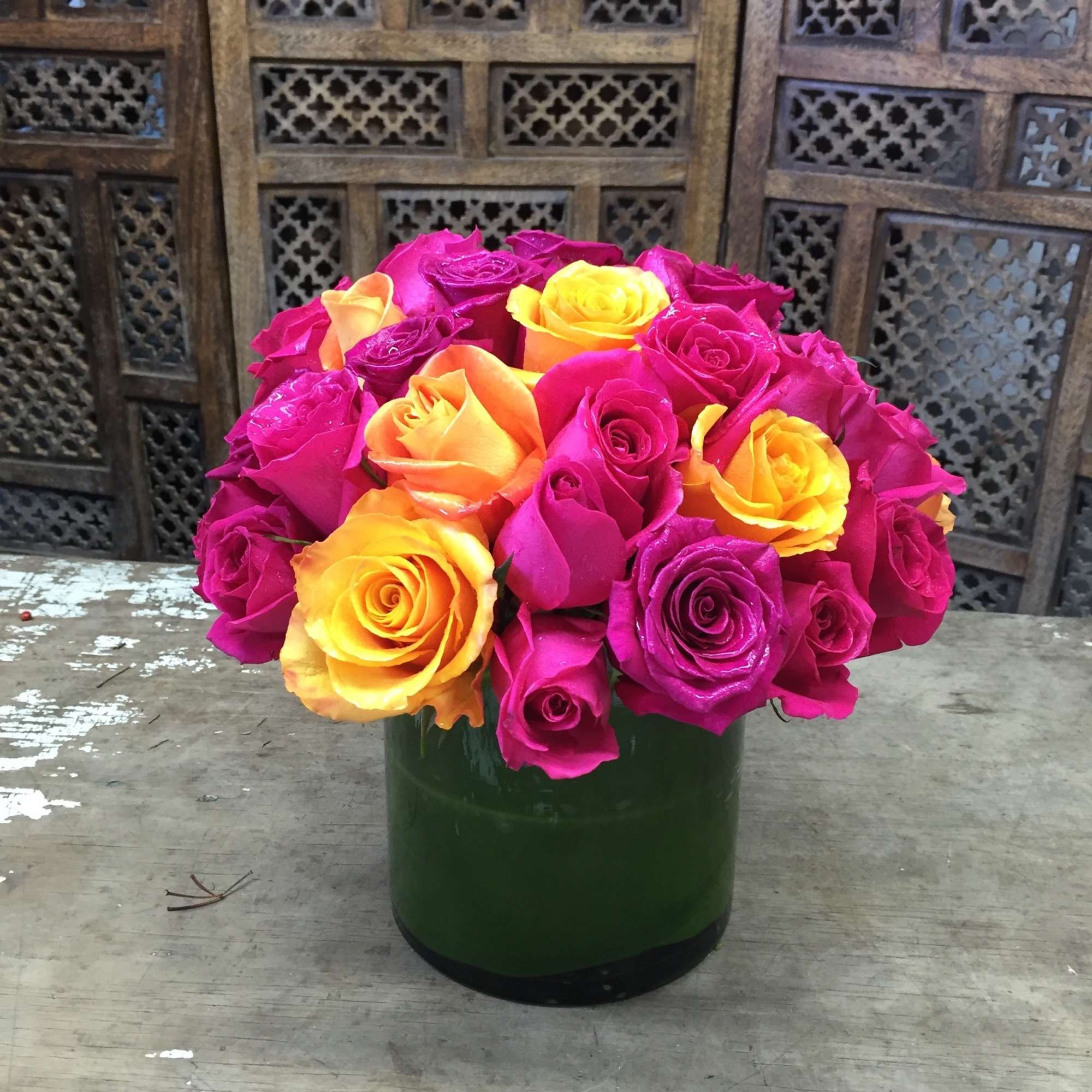 Bouquet of pink, yellow, and orange roses in a green vase