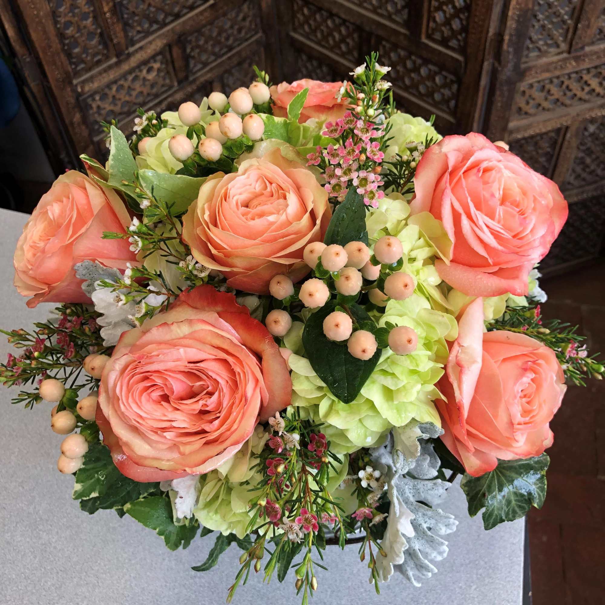 Bouquet of peach roses and pale green hydrangeas with berry accents