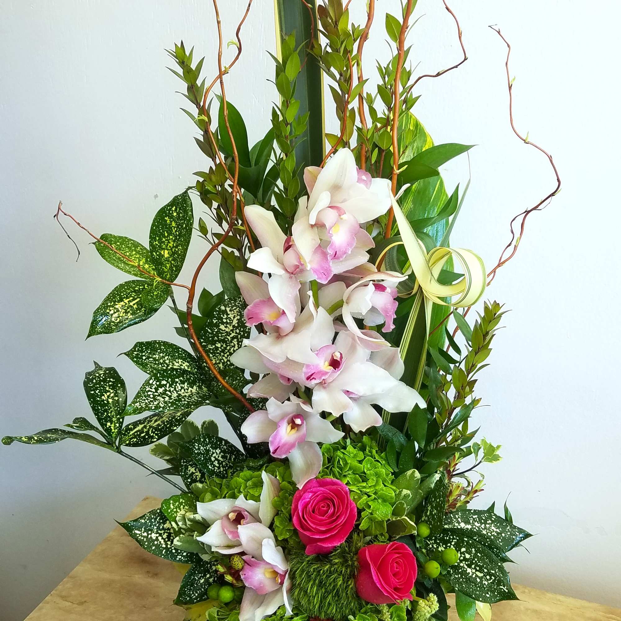 Tall floral arrangement with pink roses and white orchids in a black vase