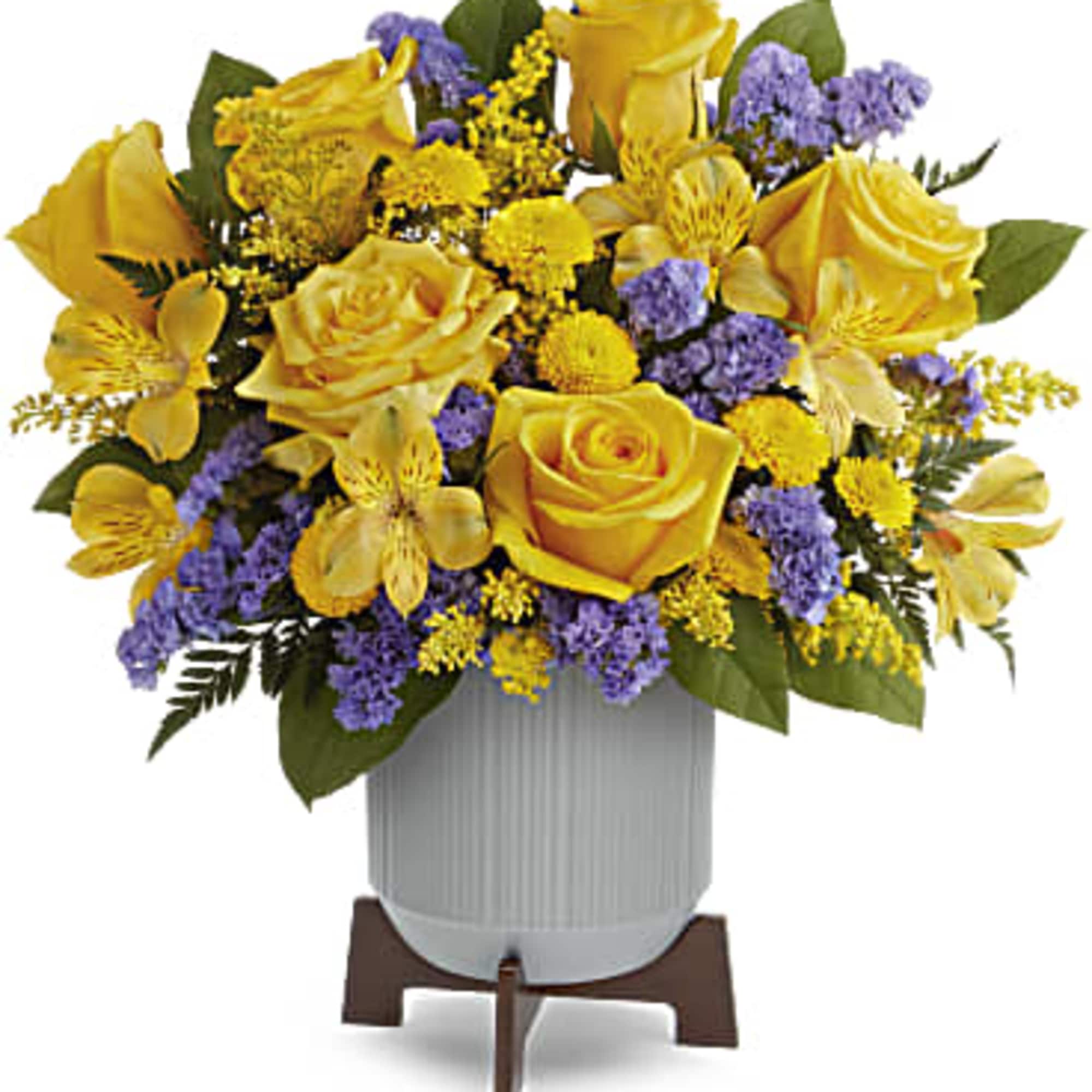 Yellow rose and purple accent flower arrangement in a white ceramic pot on a wooden stand