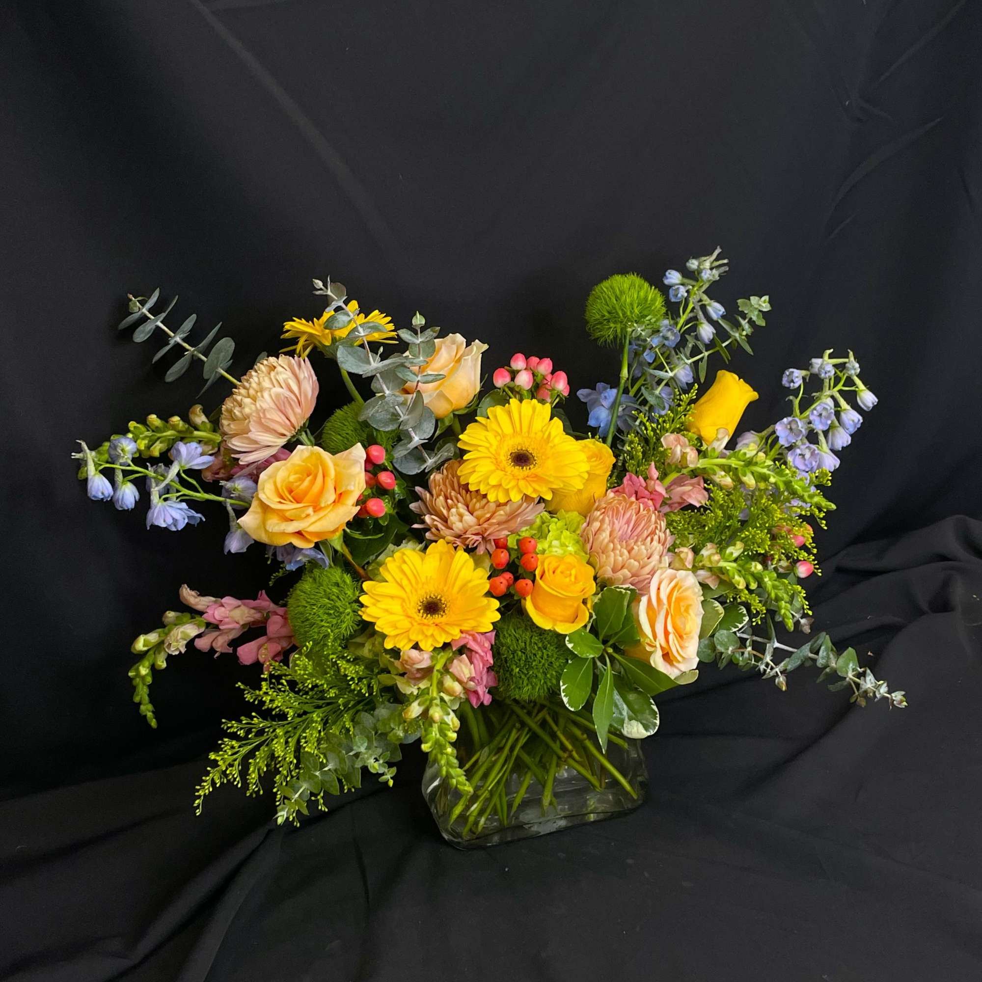 Beautiful spring colors fill a purse shaped clear vase to create a
