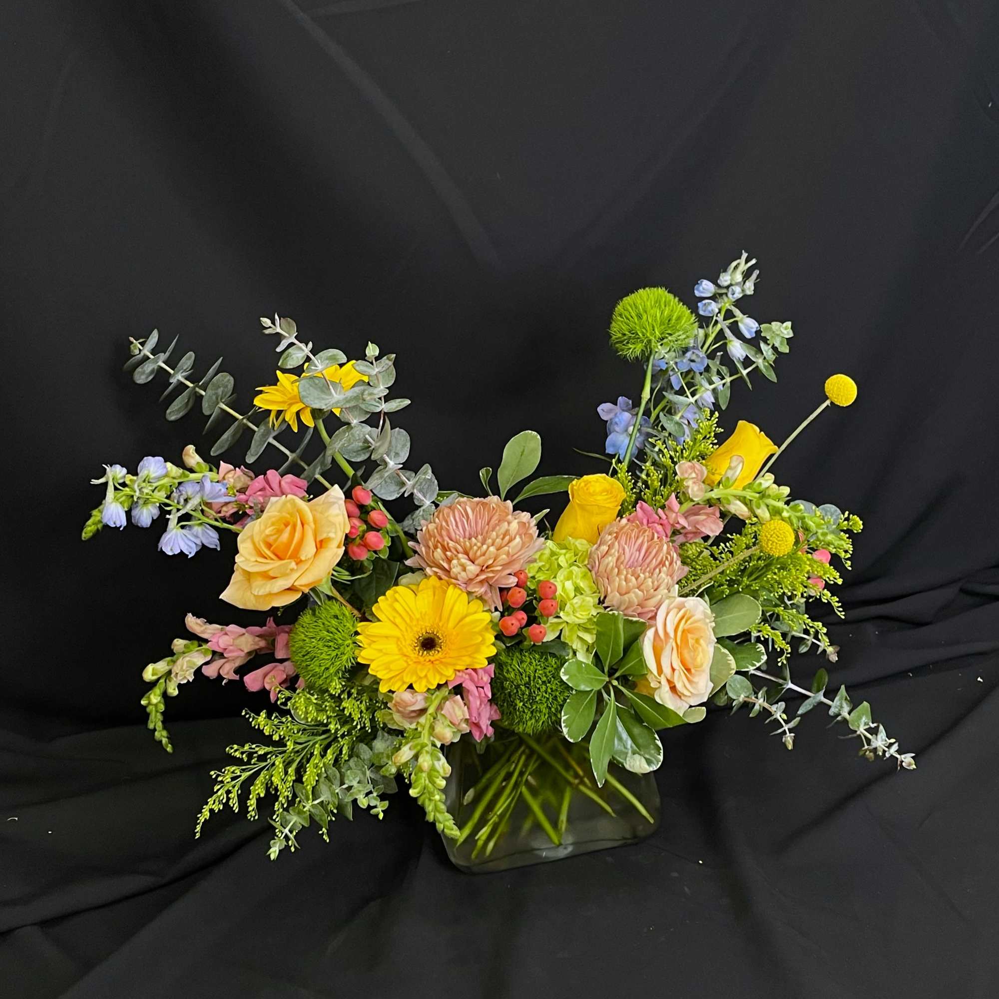Beautiful spring colors fill a purse shaped clear vase to create a