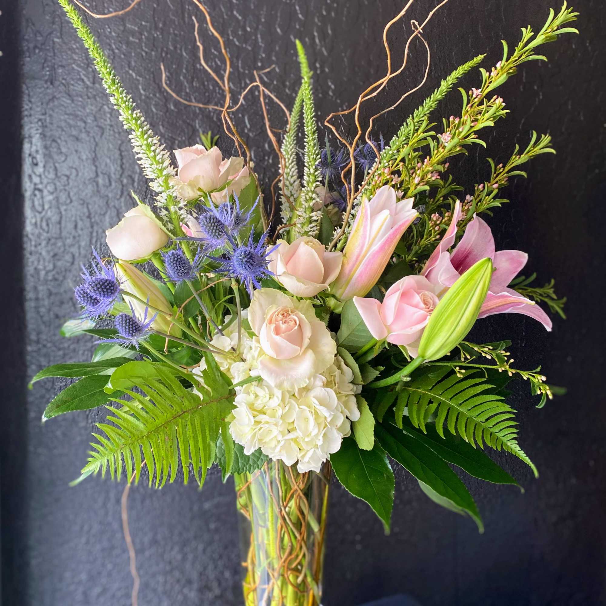 A fragrant arrangement with pink roses, lilles, and blues in a cluster-style