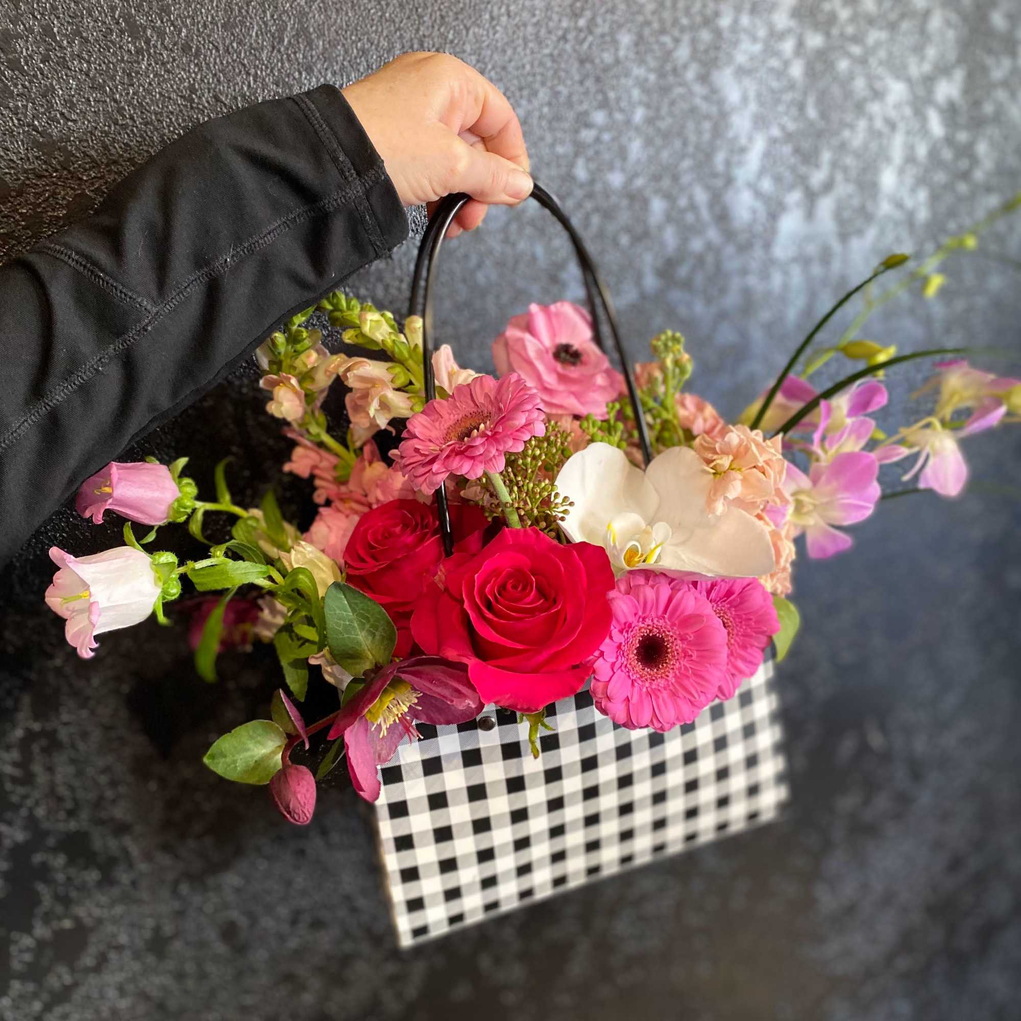 Handheld basket arrangement with pink and red flowers
