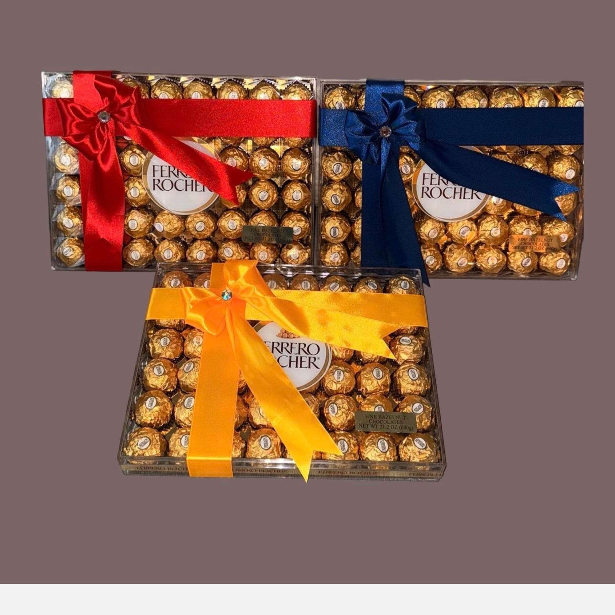 Three Ferrero Rocher chocolate gift boxes tied with red, blue, and yellow ribbons