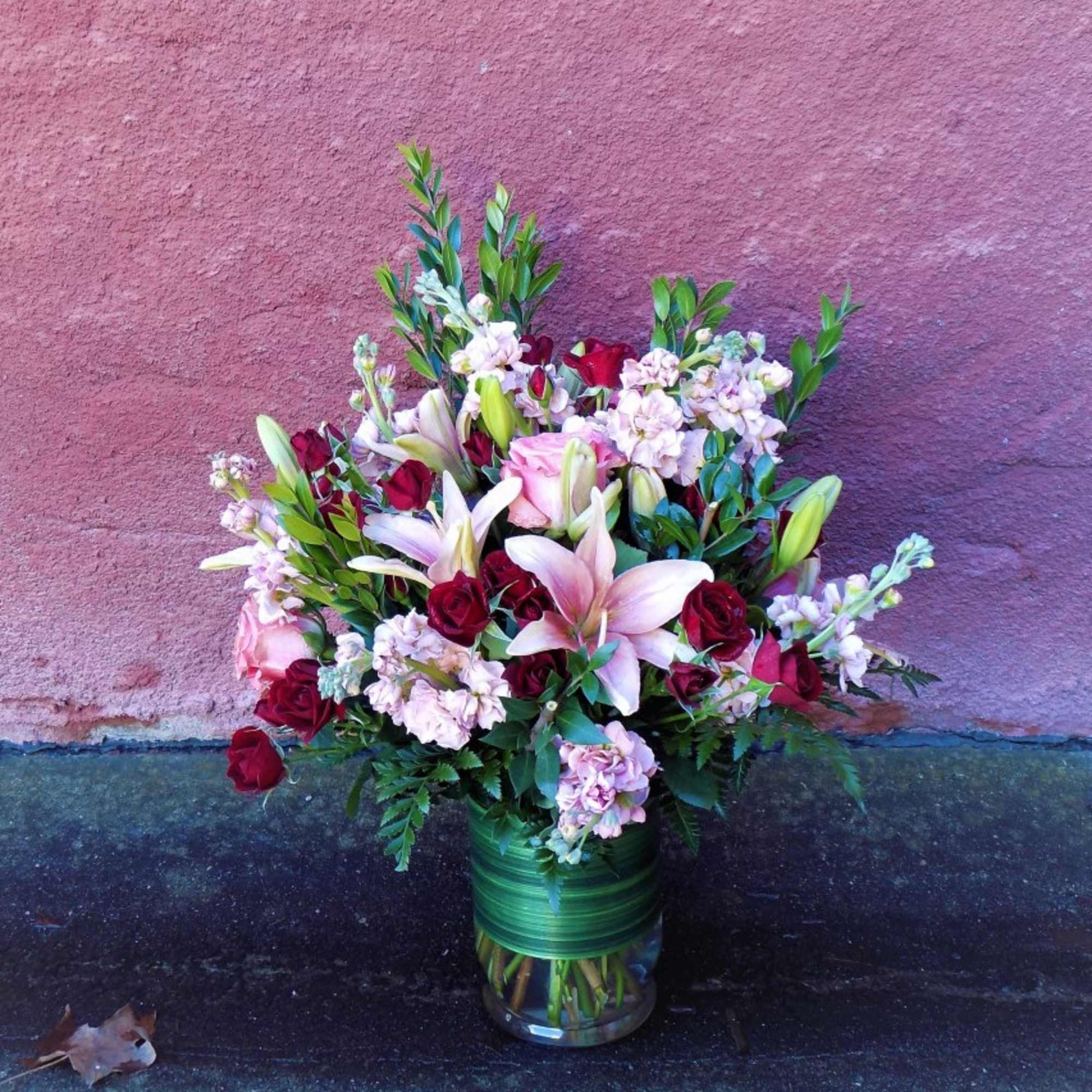 Bouquet of pink lilies and red roses in a glass vase
