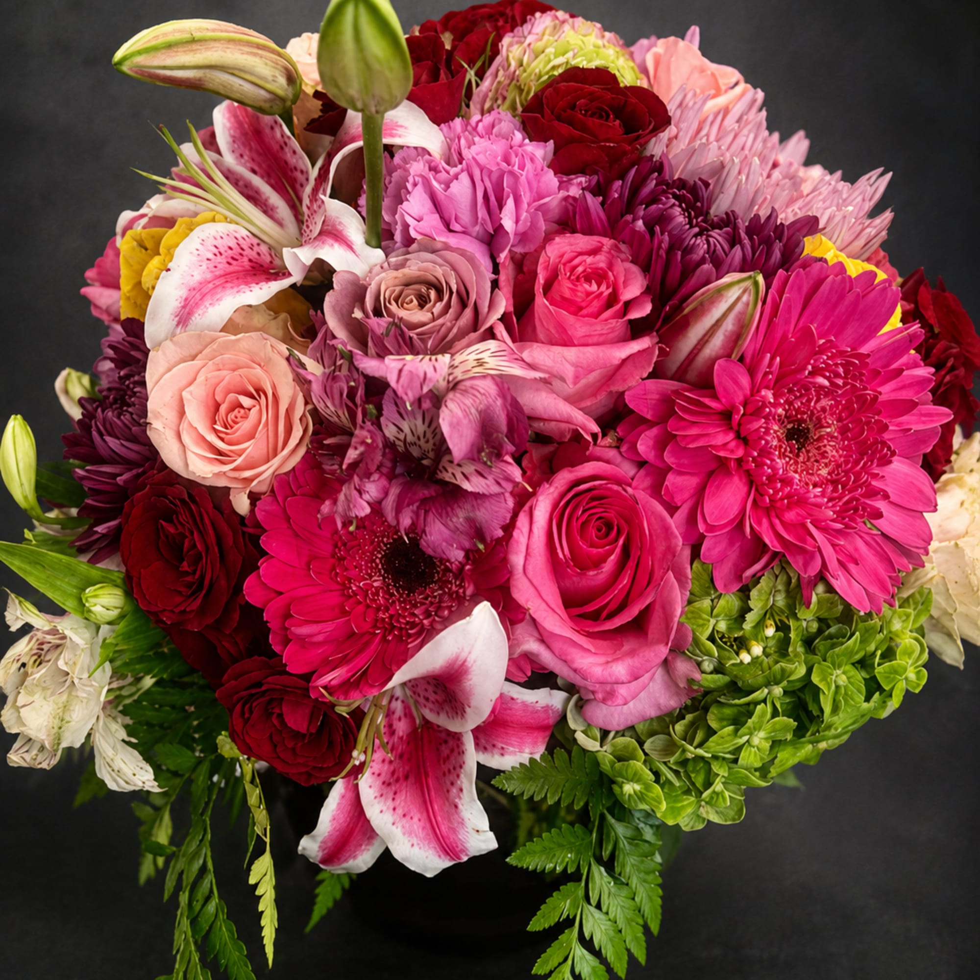 A lush, rounded bouquet bursting with pinks, reds, lavender and white, Bright
