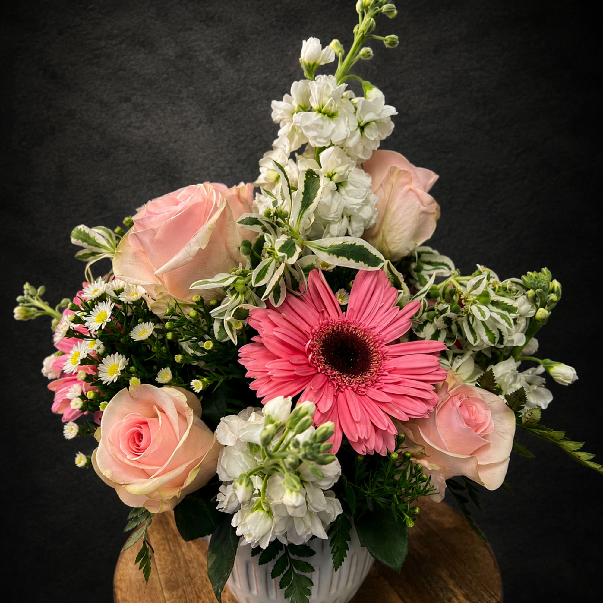 Soft pink roses and a single bright pink gerbera daisy create an