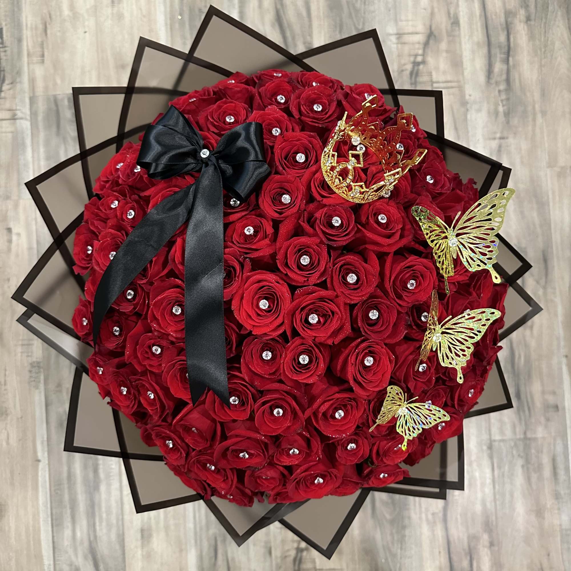 Round bouquet of red roses with a black ribbon and gold butterfly accents
