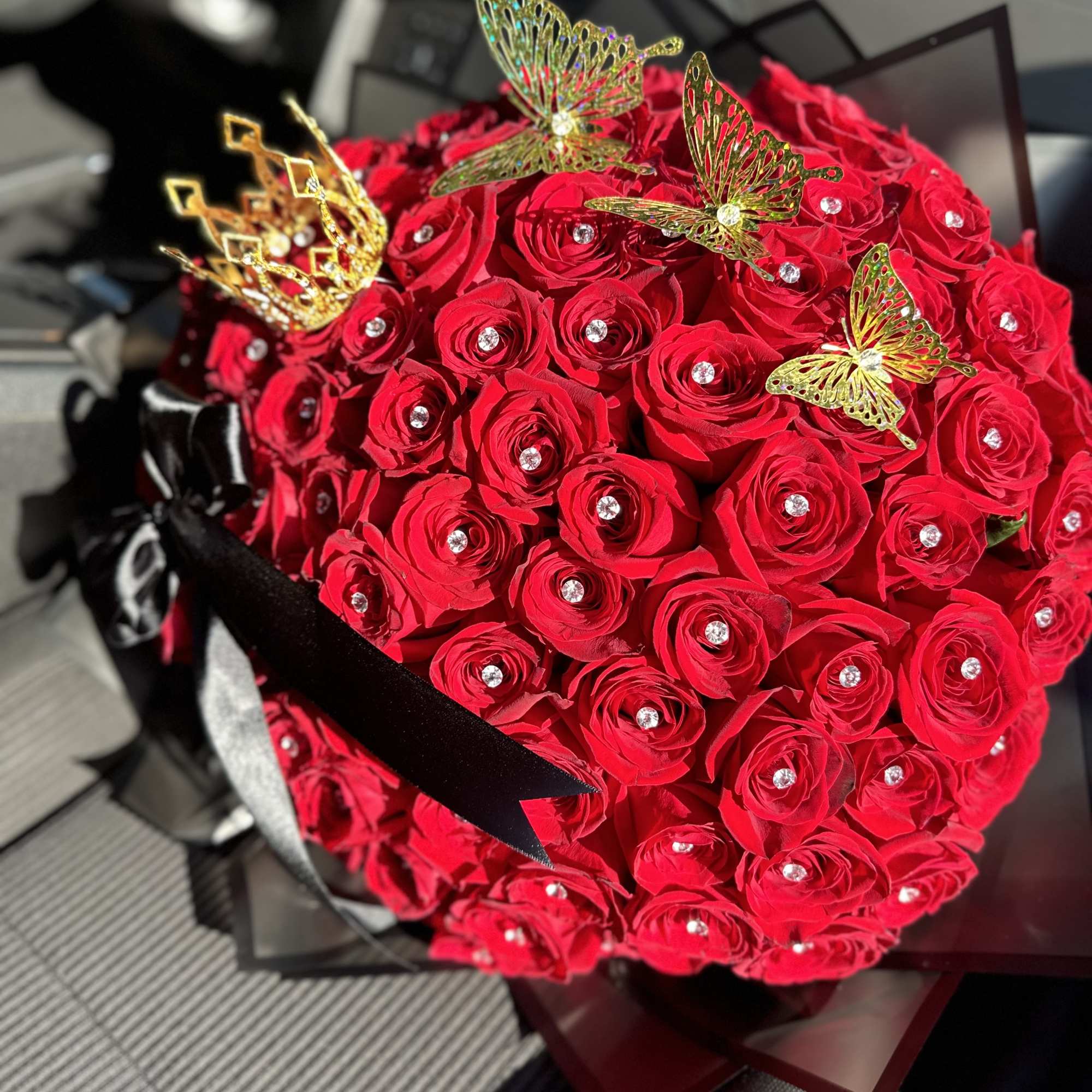 Red rose bouquet with butterfly picks and a black ribbon