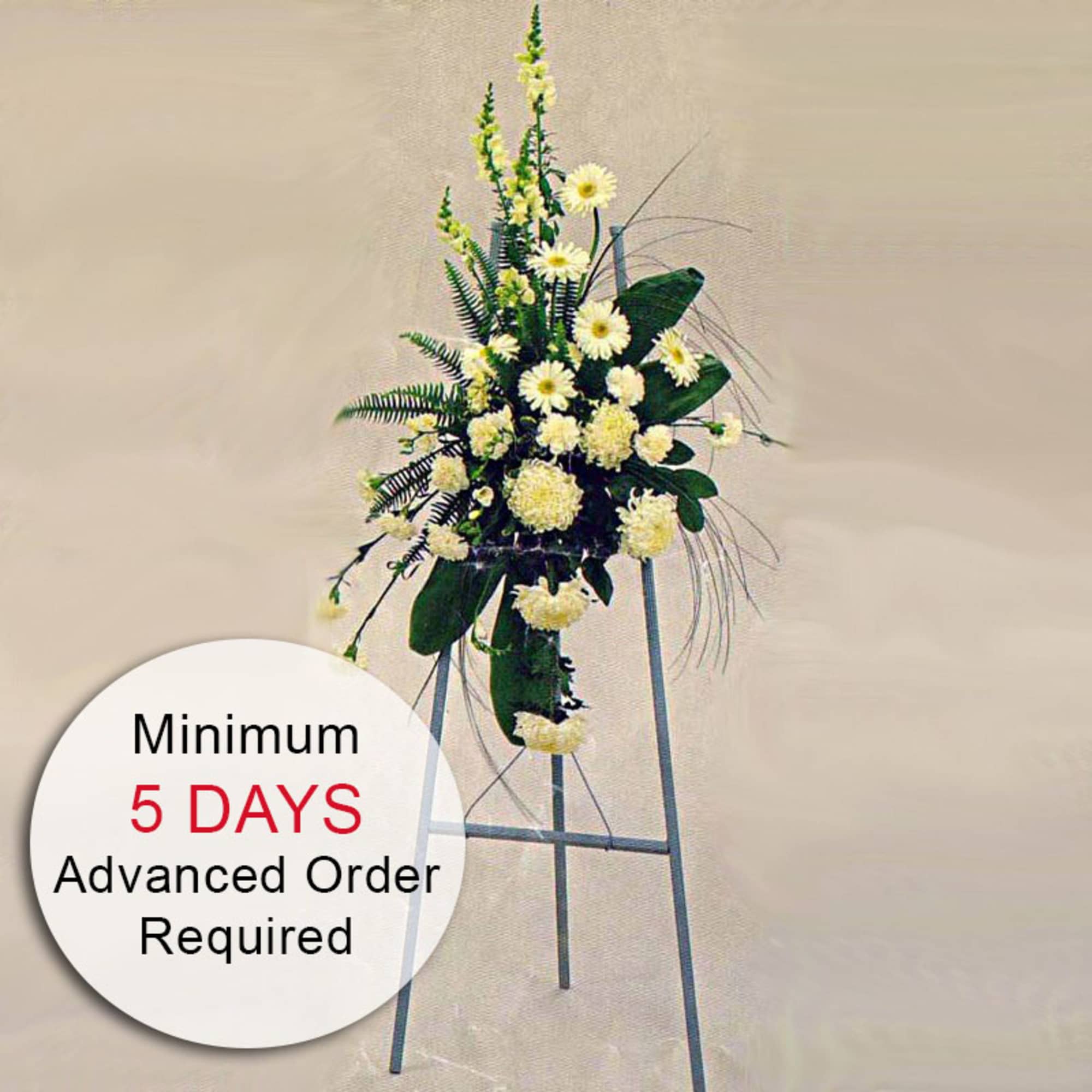 Tall white and cream standing sympathy spray on a metal easel with text noting 5 days advance order required