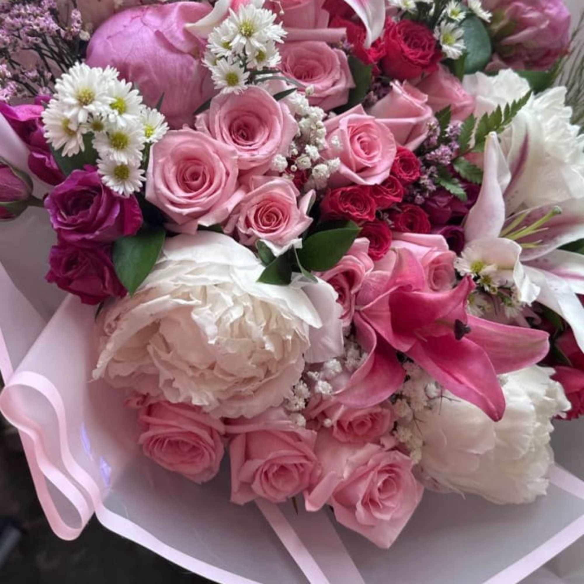Pink and white bouquet with roses, lilies, and peonies wrapped in pastel paper
