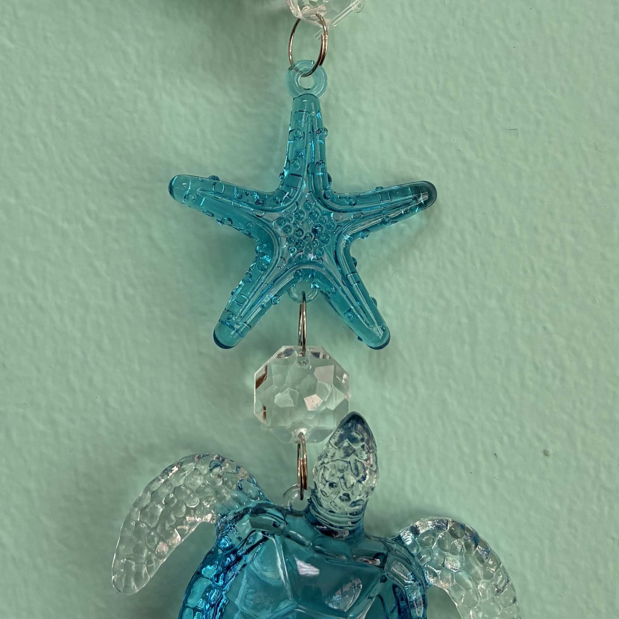 Blue crystal sea turtle and starfish hanging ornament with clear accents on a light aqua background