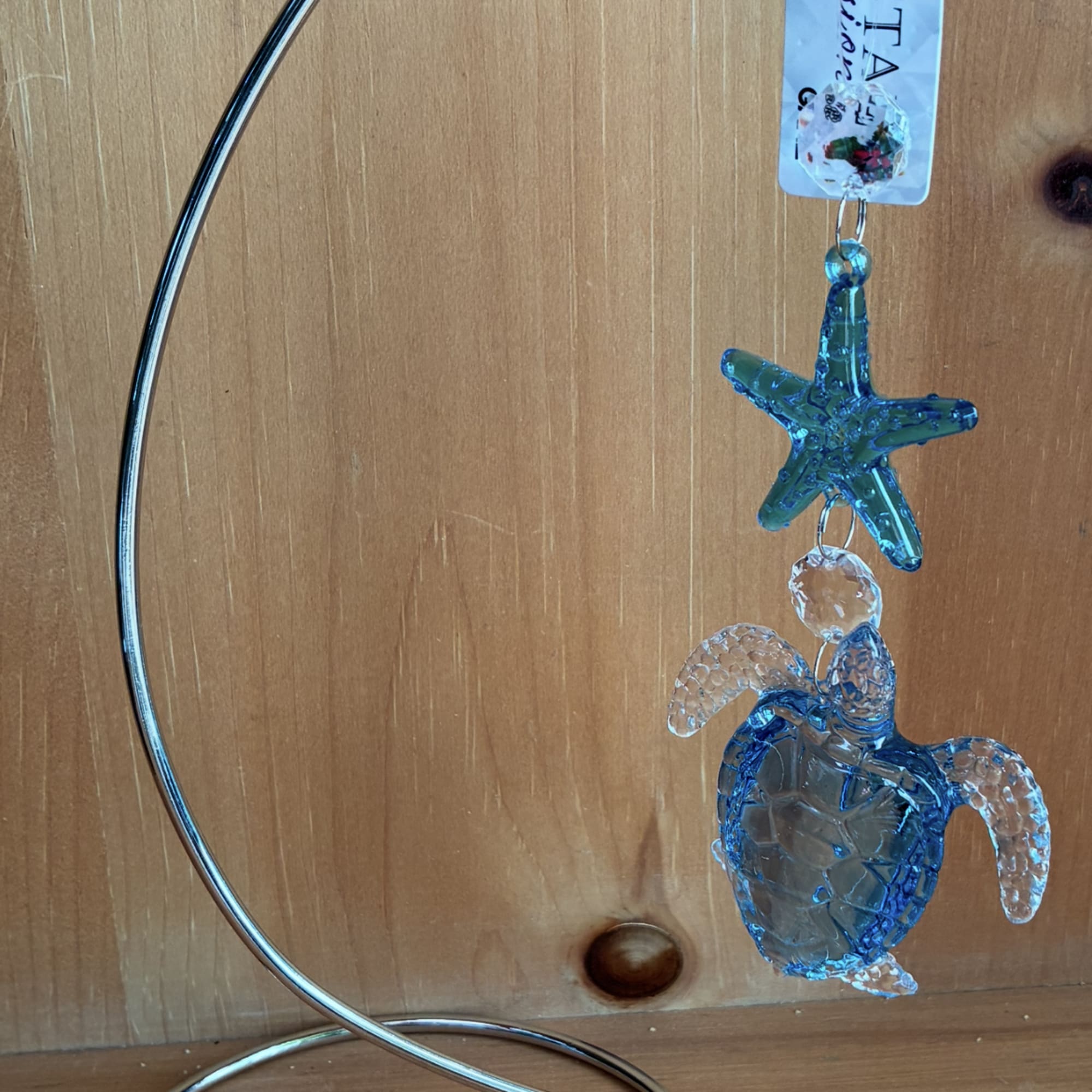 Glass sea turtle and starfish ornament hanging from a curved metal stand
