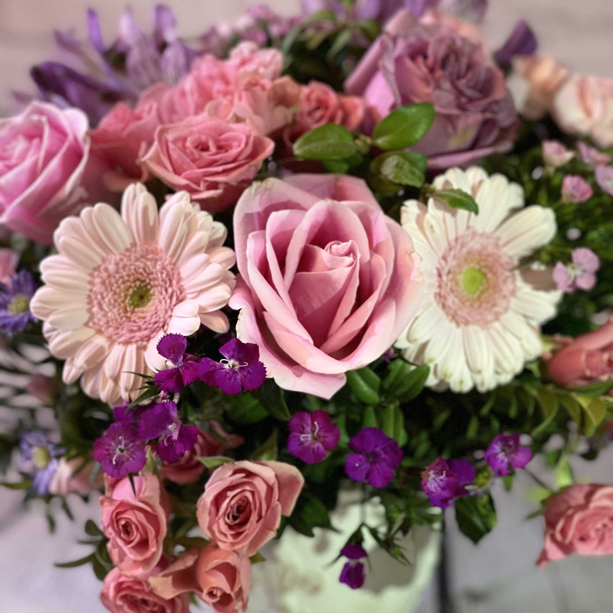 Pink and purple bouquet with roses and daisy-like blooms in a vase