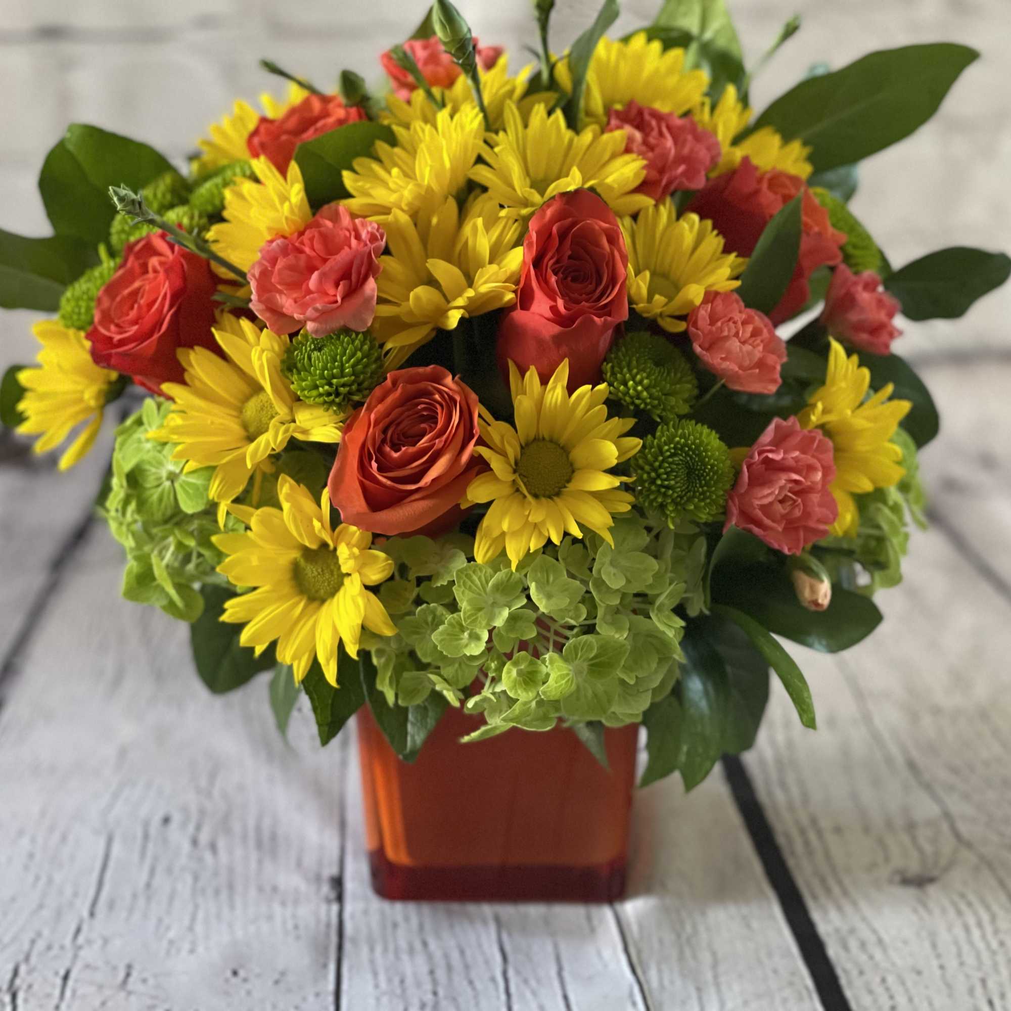 Bouquet of yellow daisies and red roses in an orange vase