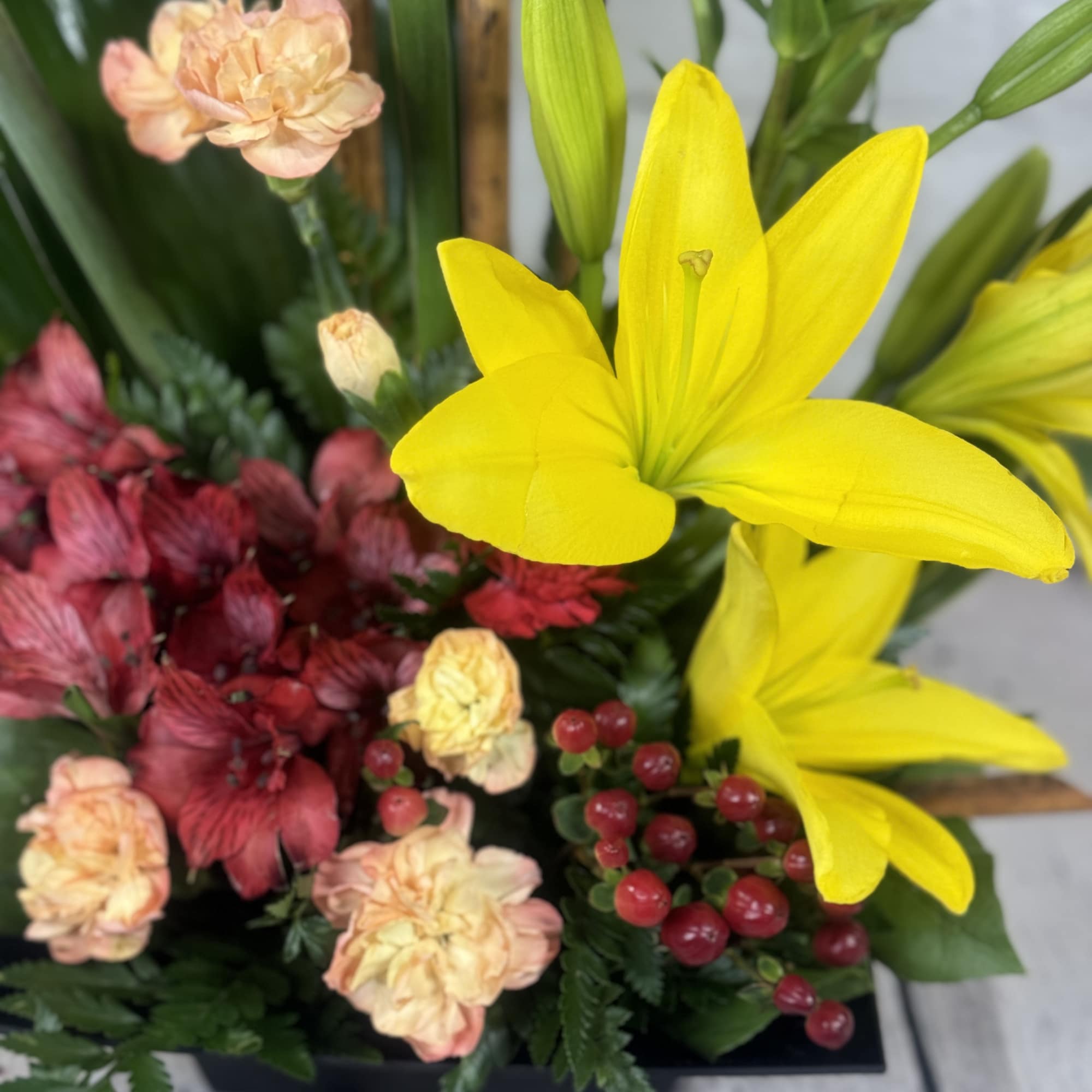 Yellow lilies with peach carnations and red alstroemeria in a low arrangement
