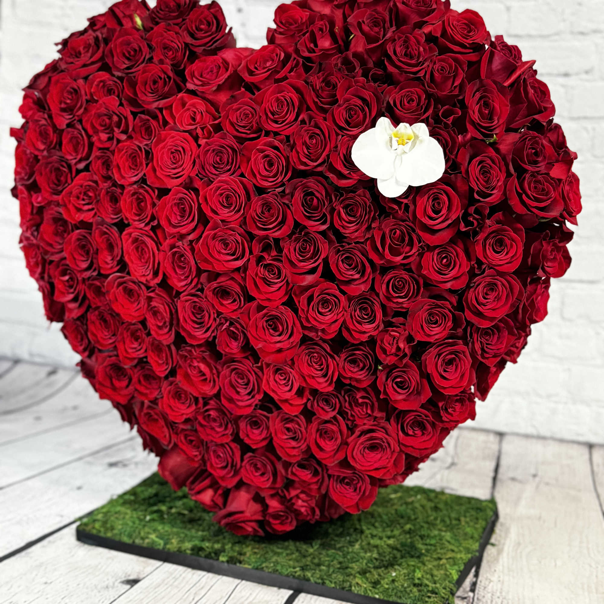 Heart-shaped arrangement of red roses with a white orchid accent, photo 3 of 4