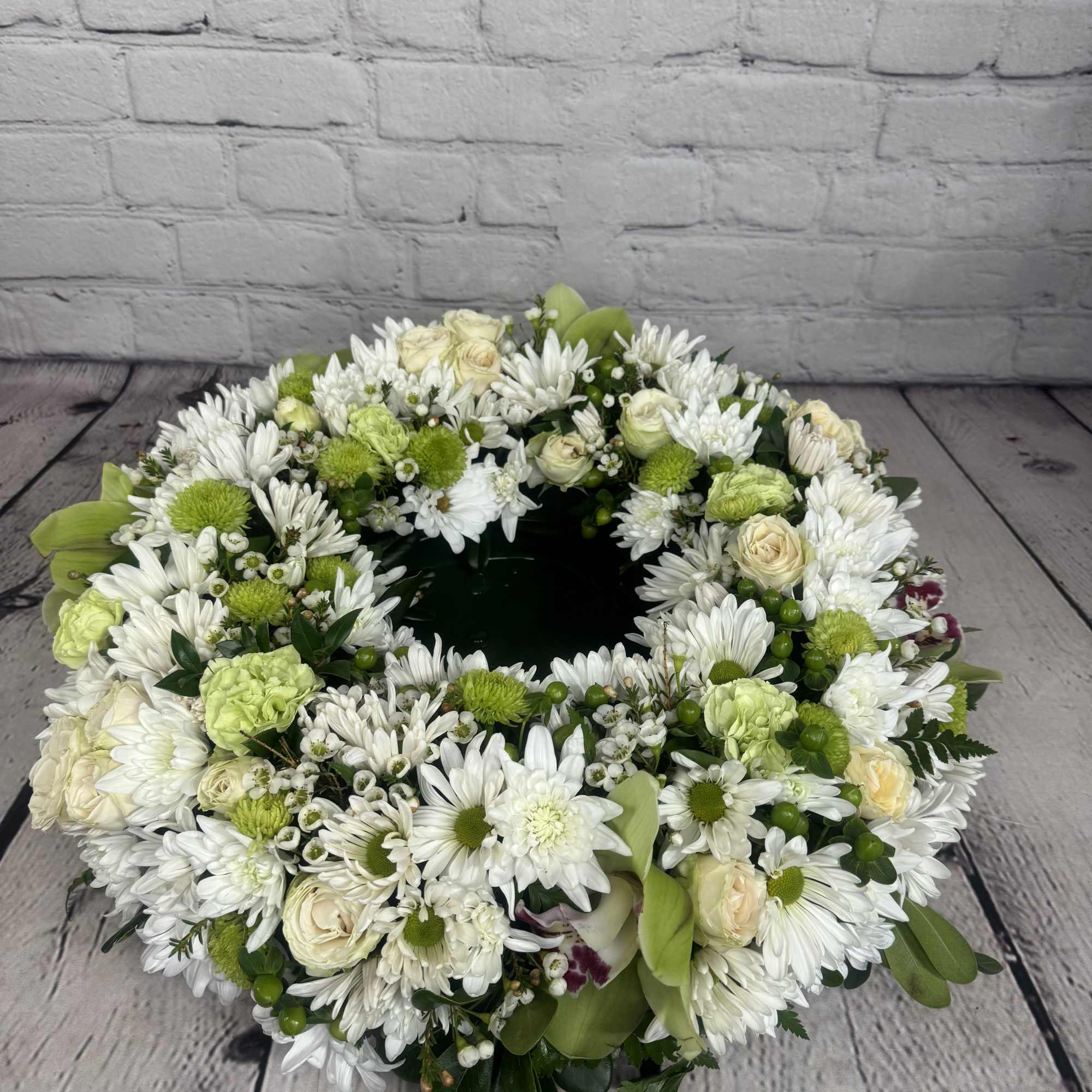 Circular floral wreath of white and green flowers on a dark base