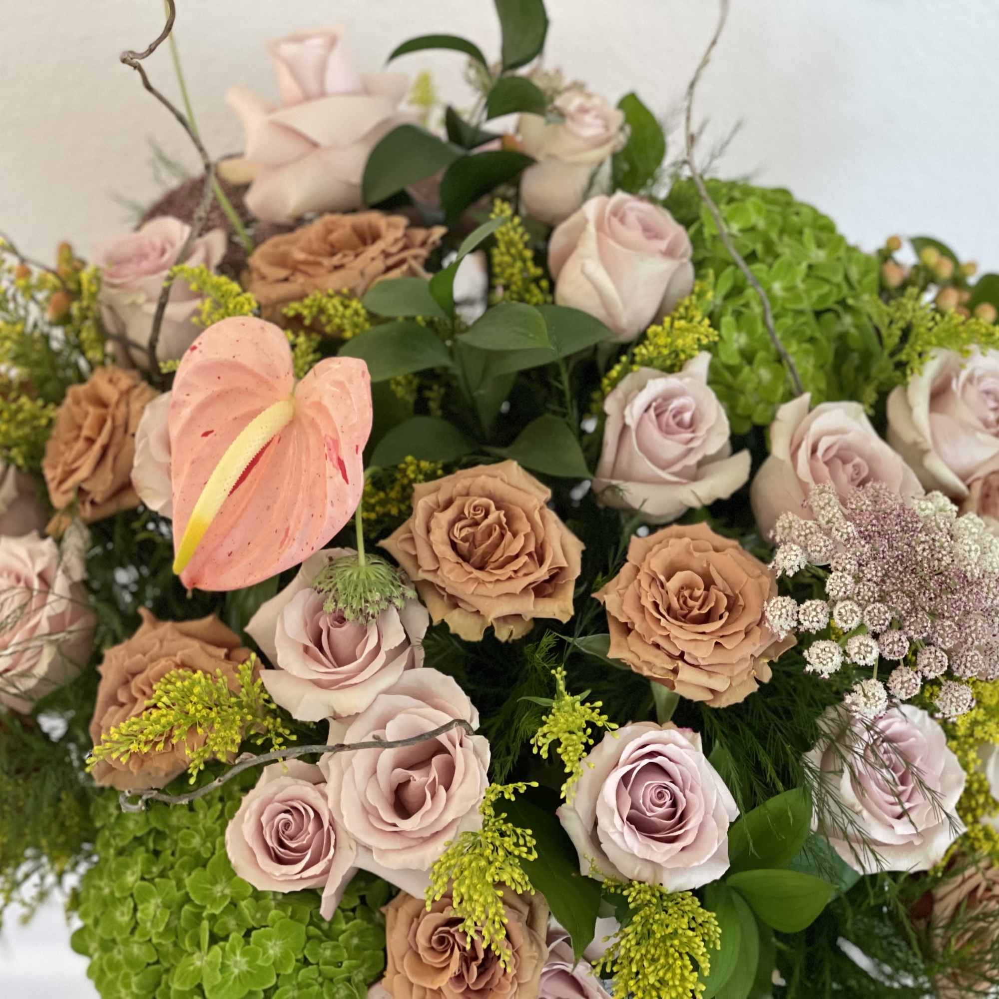 Large bouquet of blush and tan roses with green hydrangea and an anthurium