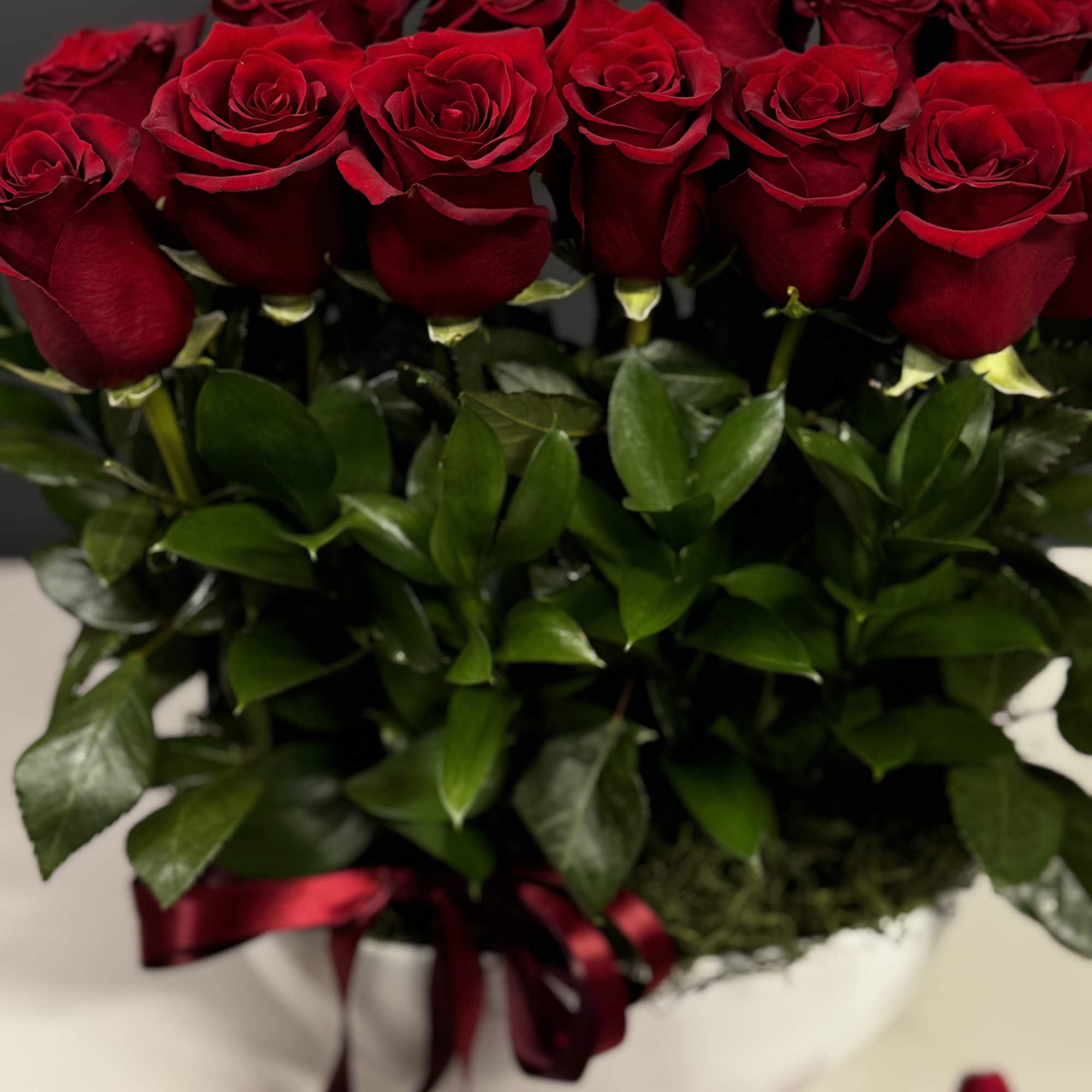 Bouquet of red roses in a white box with a burgundy ribbon