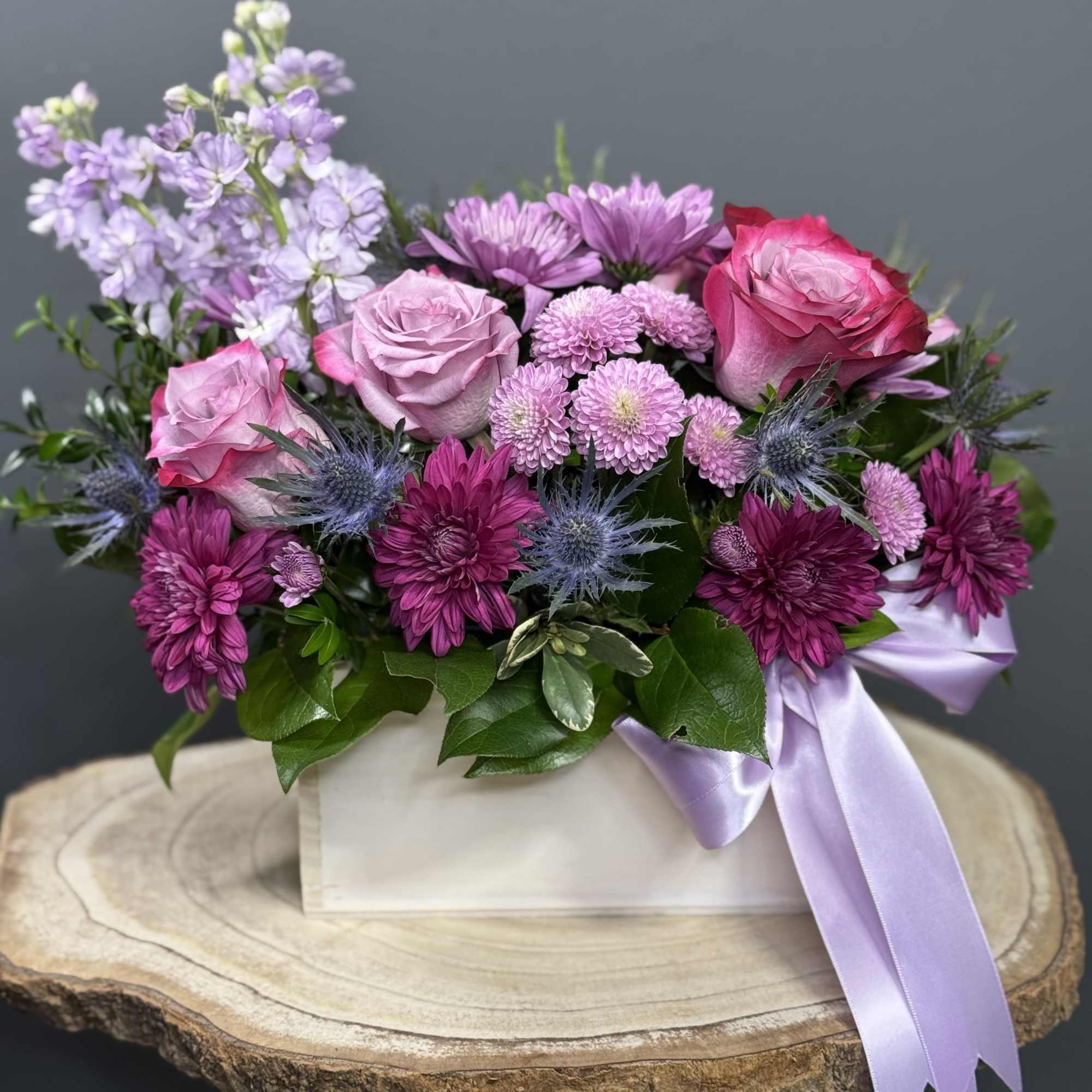 Pink and purple flower arrangement in a white box with a lavender ribbon