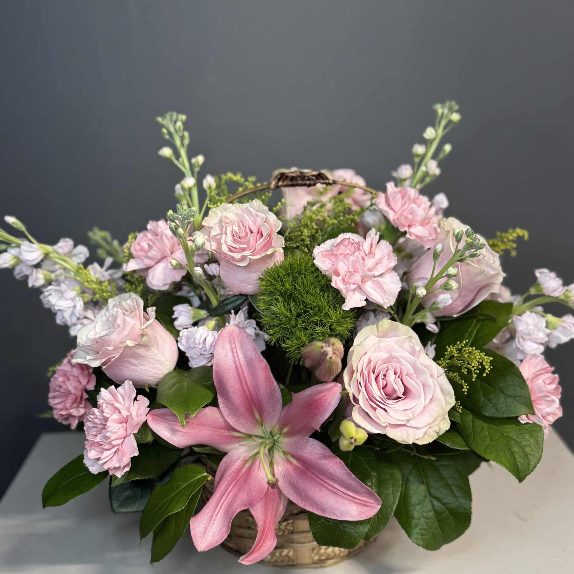 Pink roses and lilies arranged in a woven basket