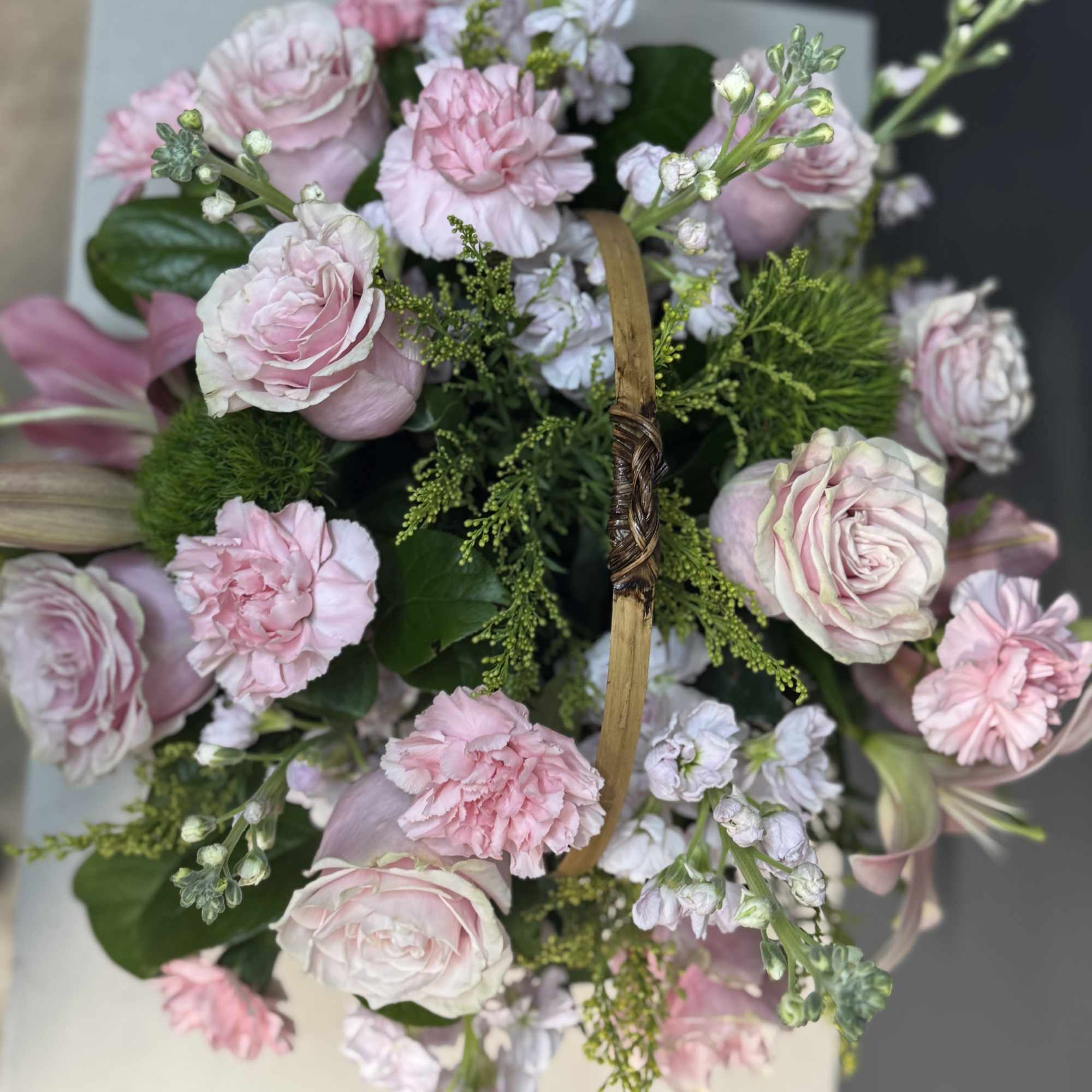 Pink and white bouquet with roses and carnations in a basket