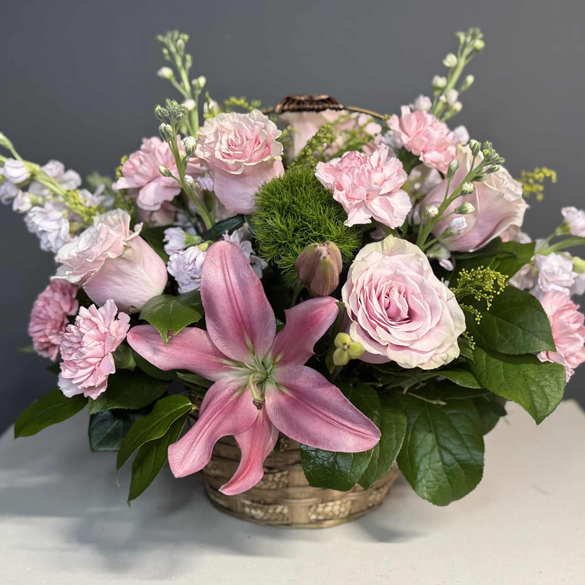 Pink roses and lilies arranged in a low basket
