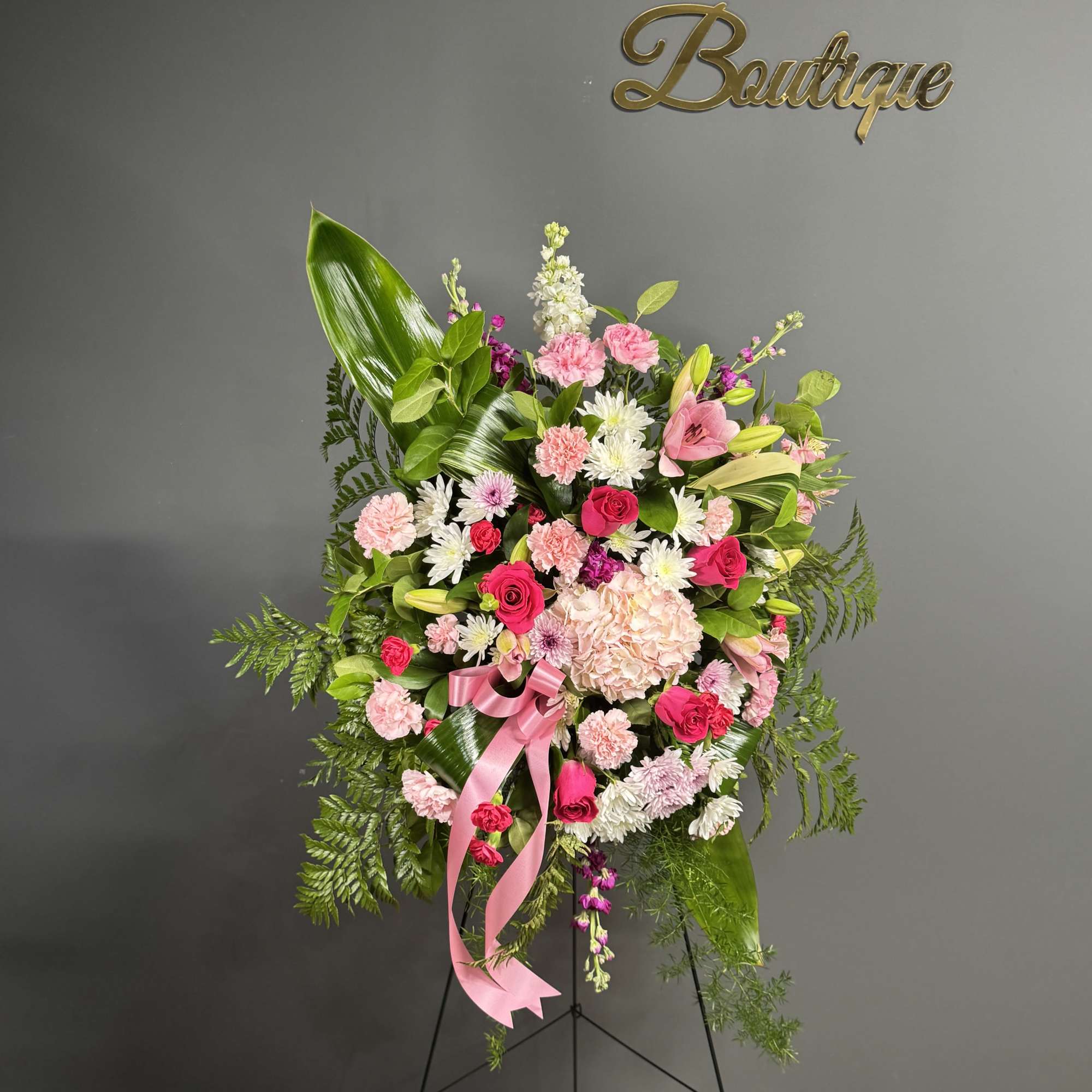 Standing floral spray with pink and white blooms on a black easel