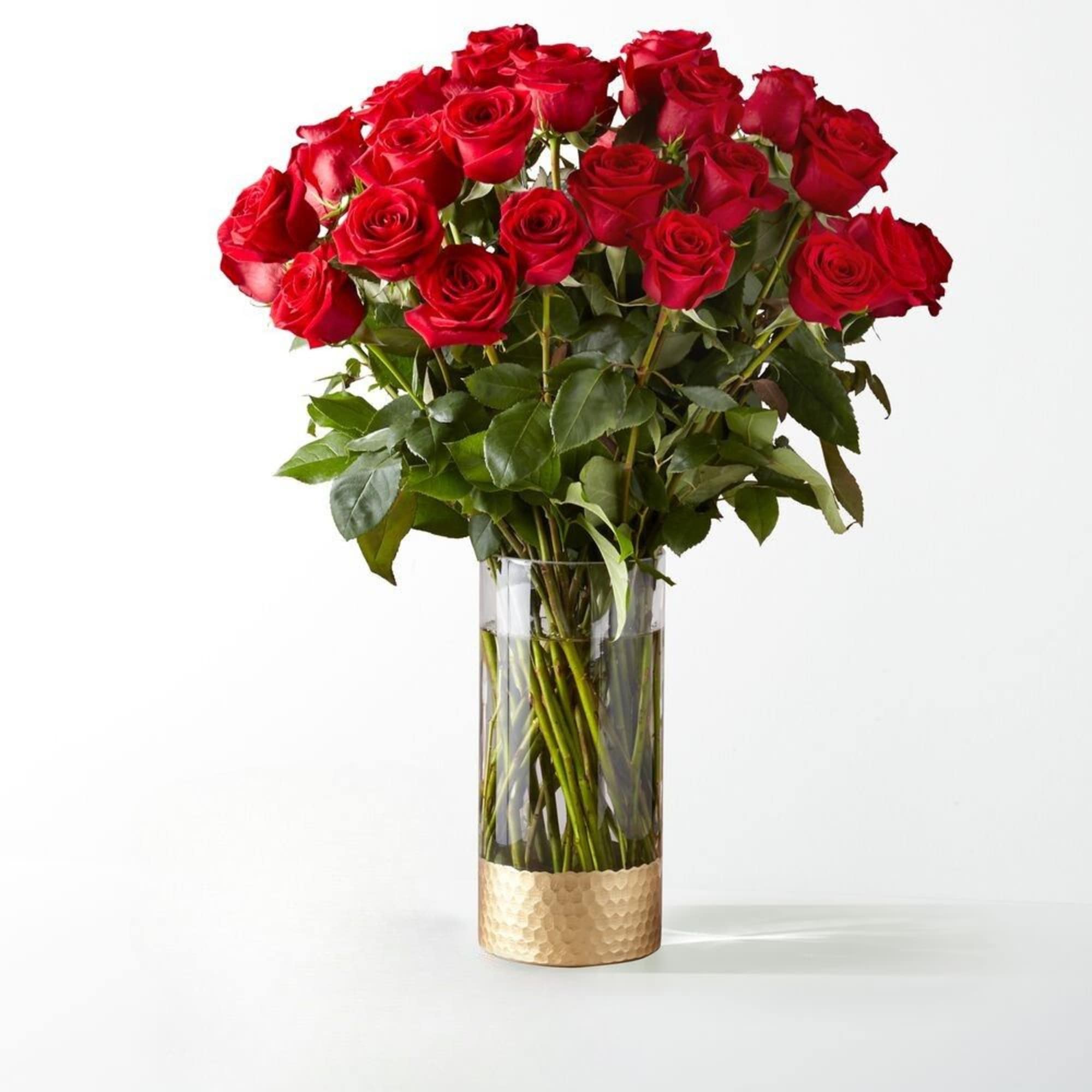 Red roses in a clear glass vase with a gold base